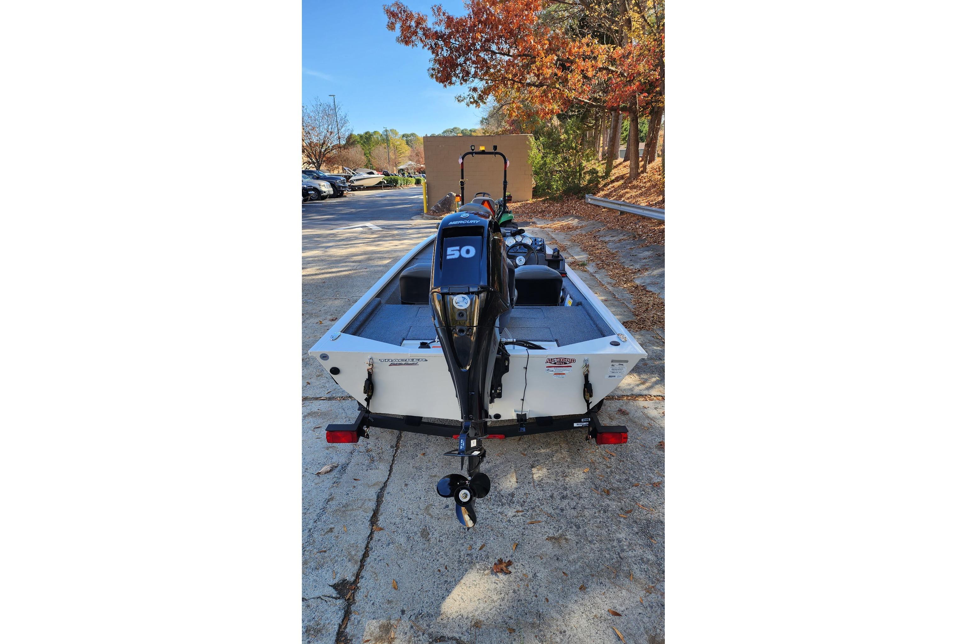 2026 Tracker Pro 170 boat with 50 HP motor, parked on a leaf-covered driveway.