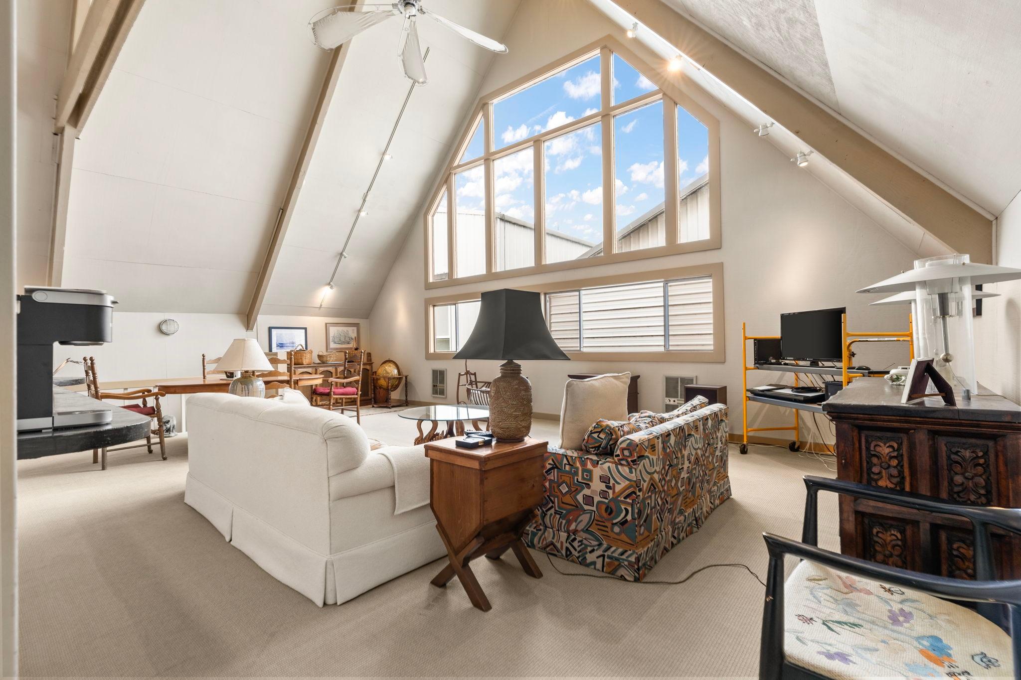 Spacious 1976 custom boathouse interior with vaulted ceilings, large windows, and eclectic furnishings.
