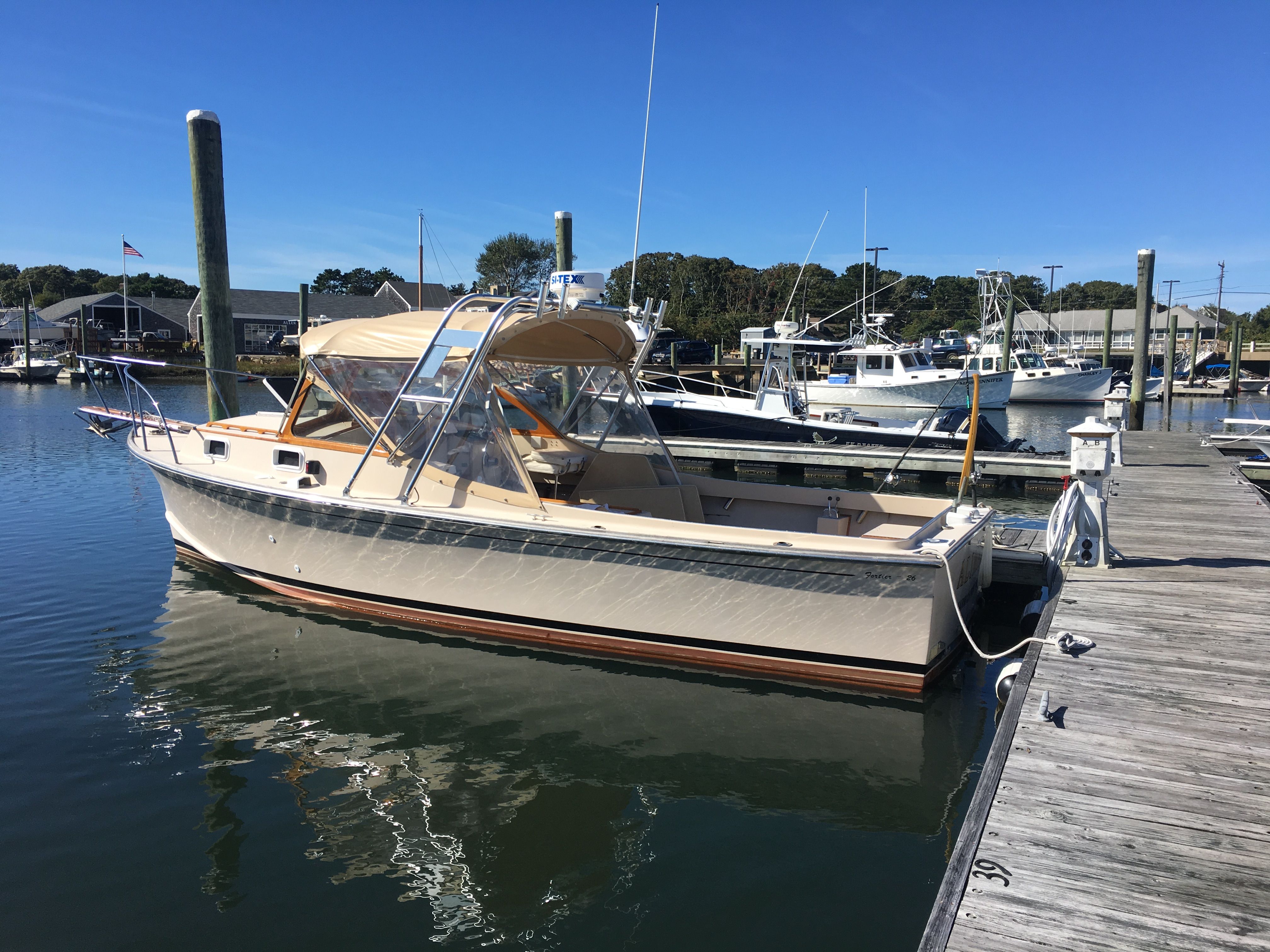 A 1989 Fortier 26 boat docked at a calm harbor pier.