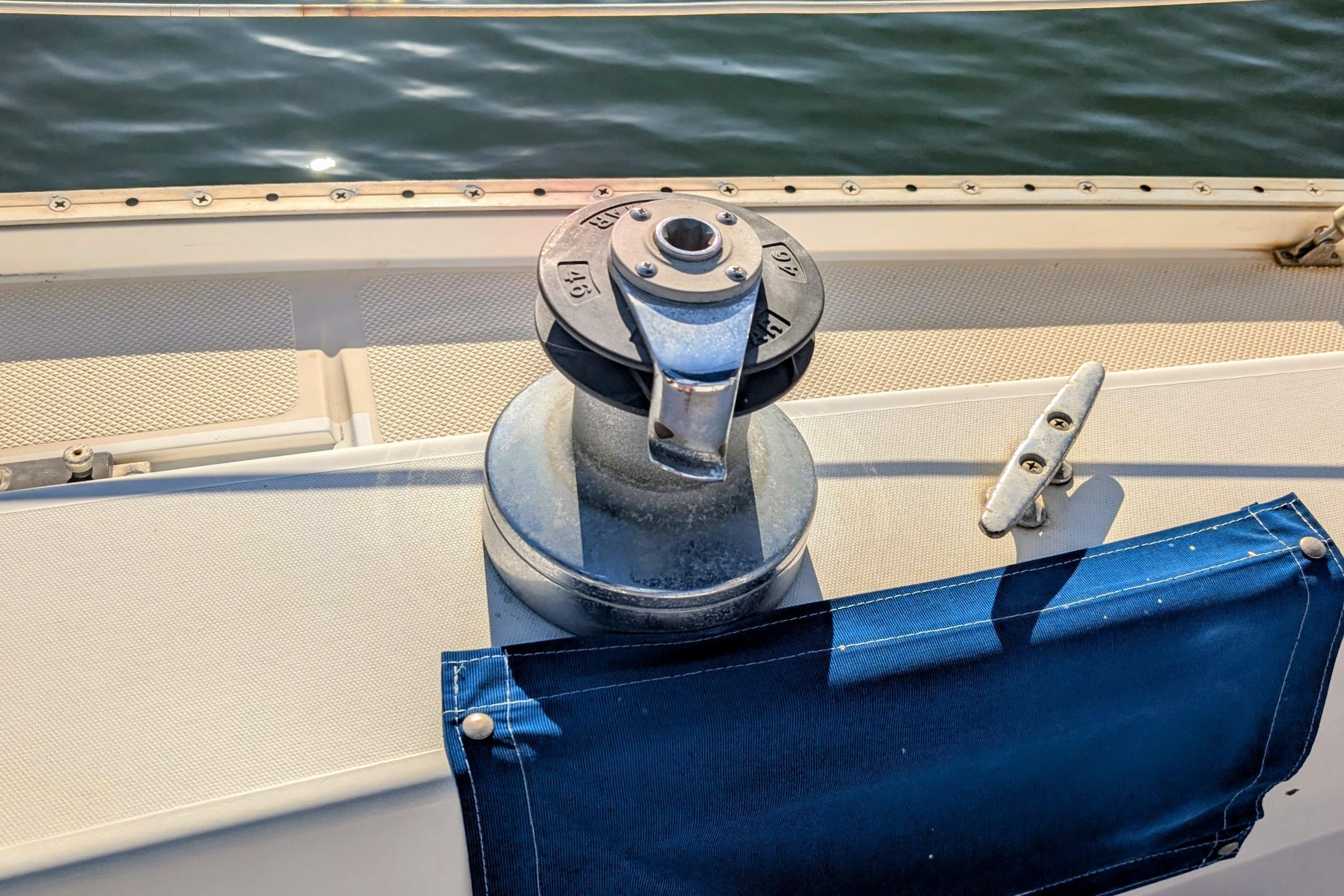 Winch and cleat on 1989 Catalina 34 sailboat deck by the water.