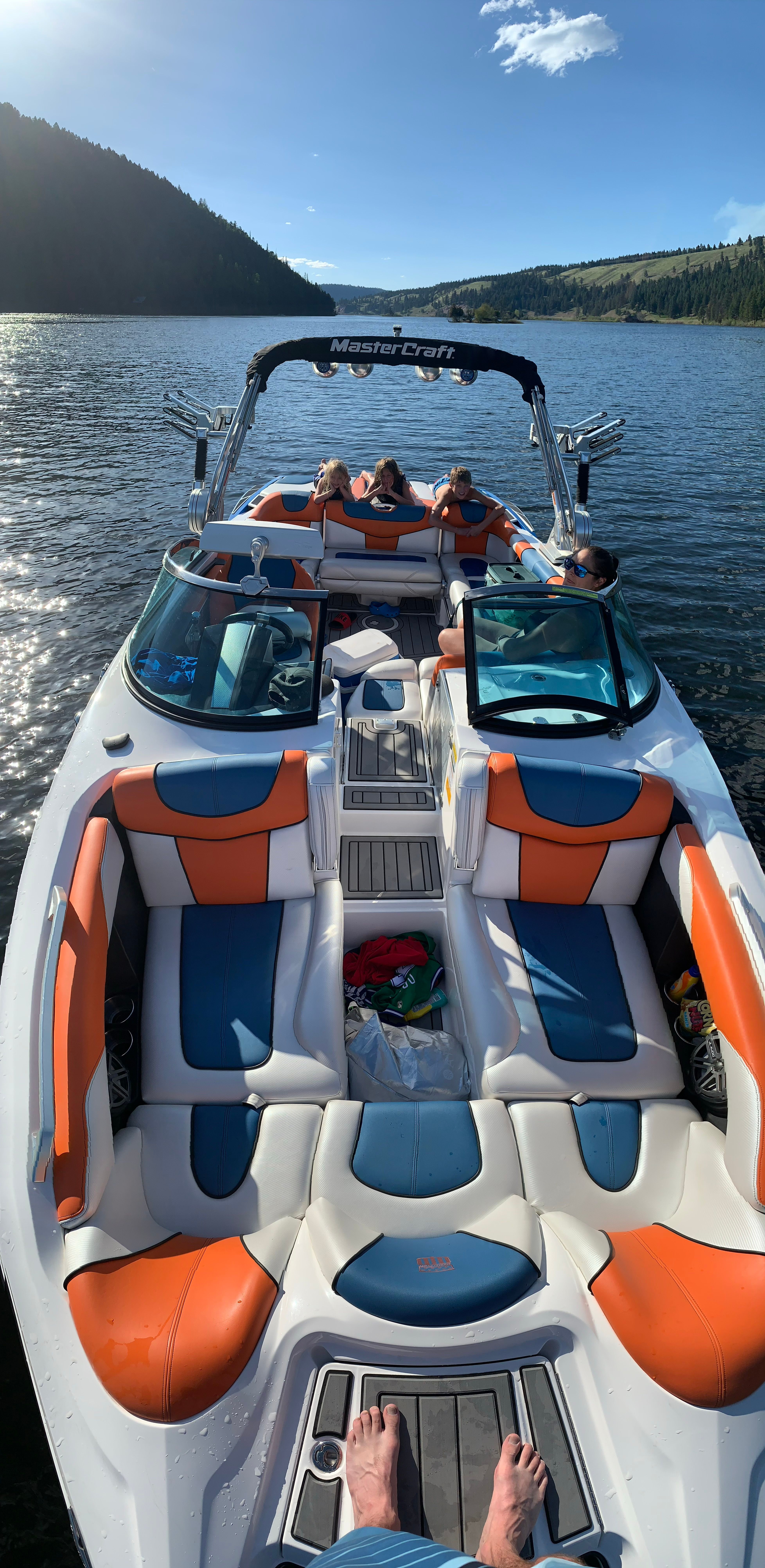 2013 MasterCraft XStar boat on a serene lake with passengers.