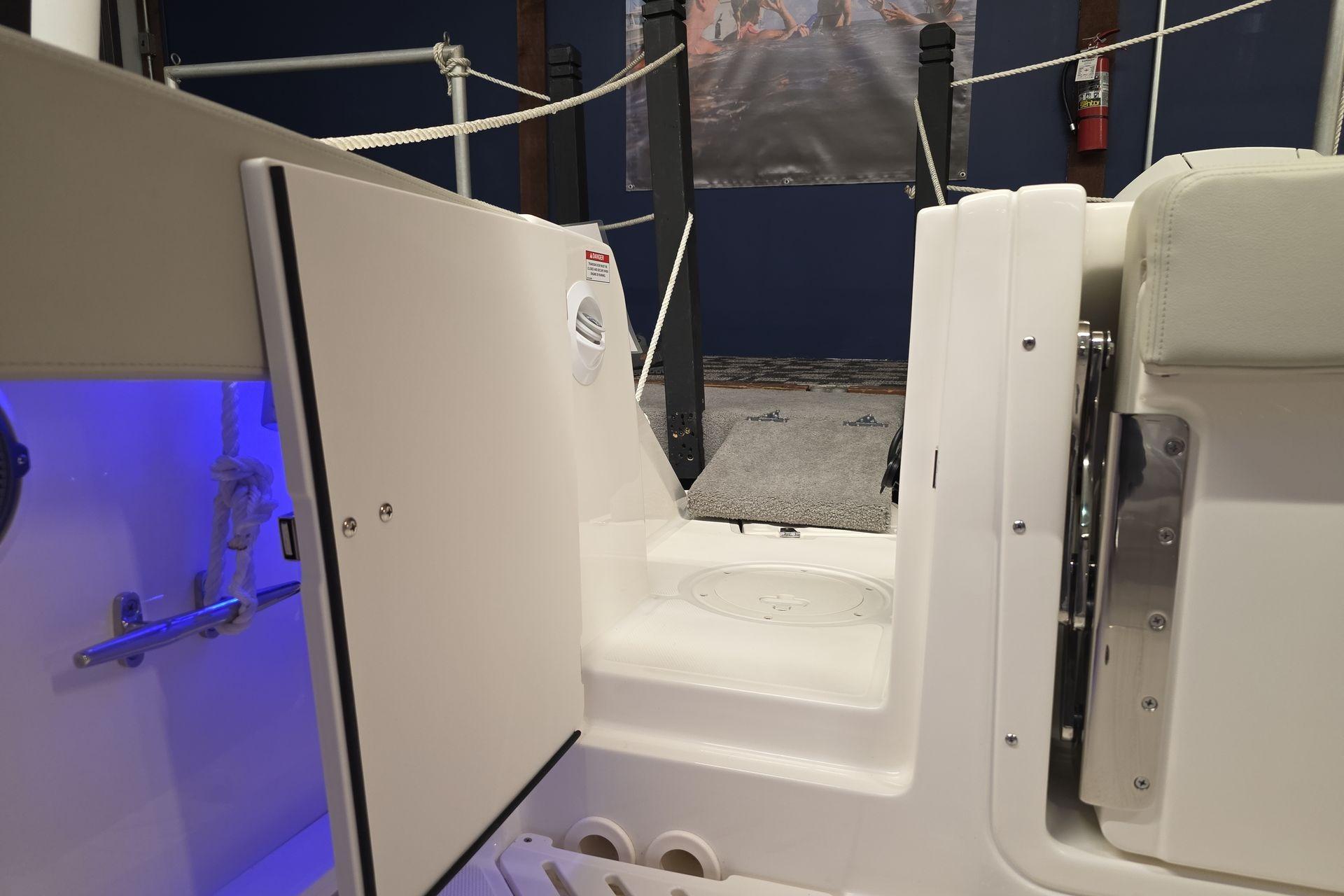 2025 Boston Whaler 240 Vantage interior with open storage compartment and blue lighting.