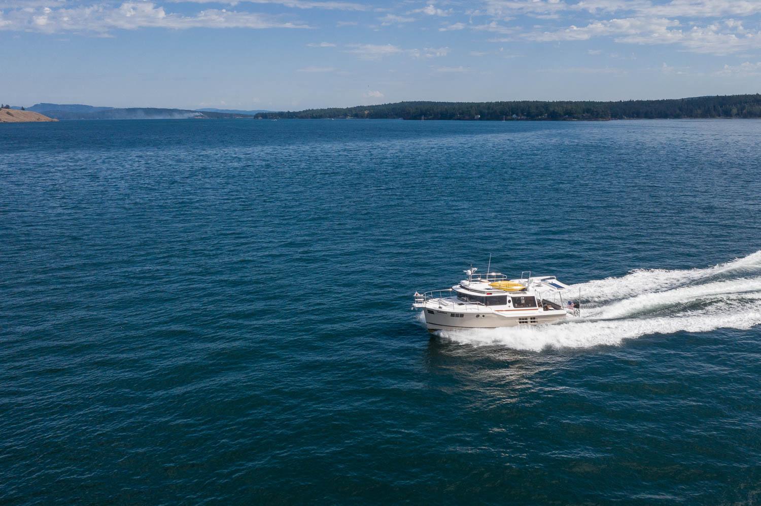 2025 Ranger Tugs R-43 S cruising on open water under a clear sky.