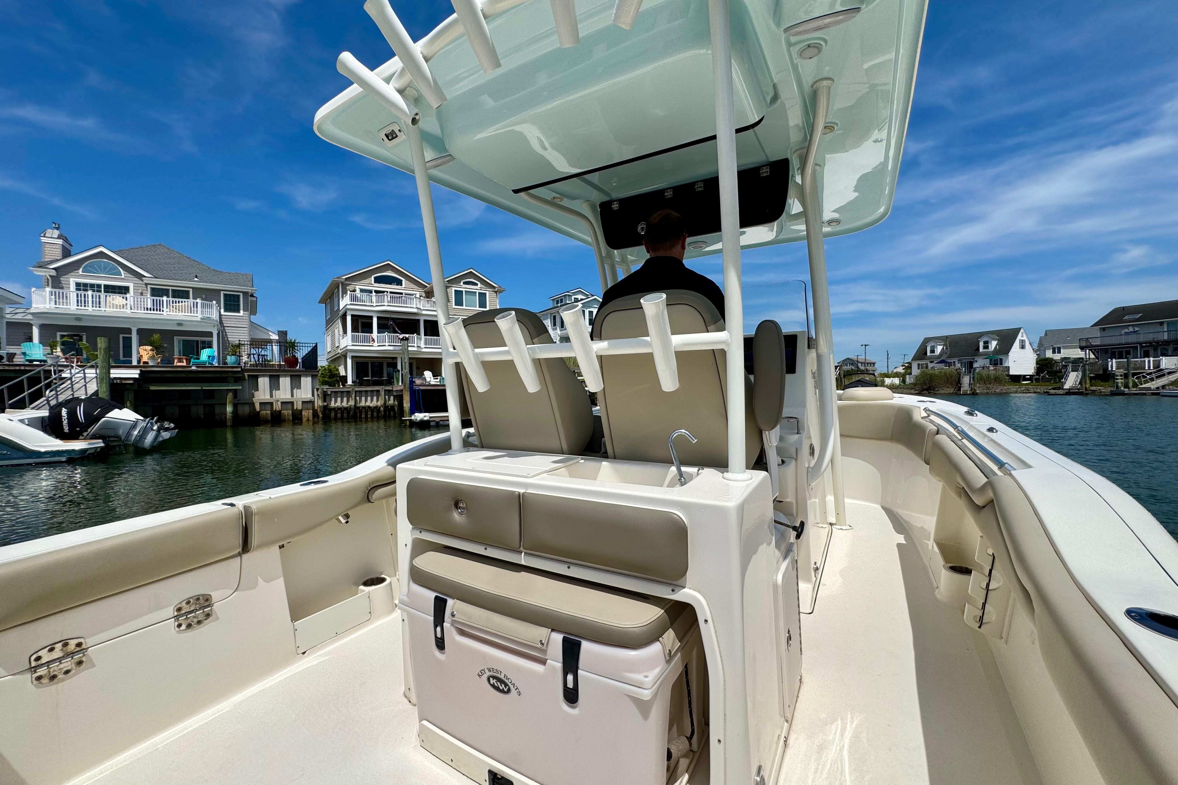 2022 Key West 263 FS boat cruising near waterfront homes under a clear blue sky.