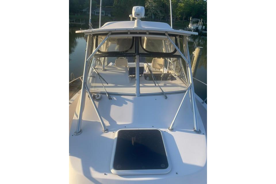 2002 Grady-White Marlin 300 boat with enclosed cockpit, docked in a serene marina setting.