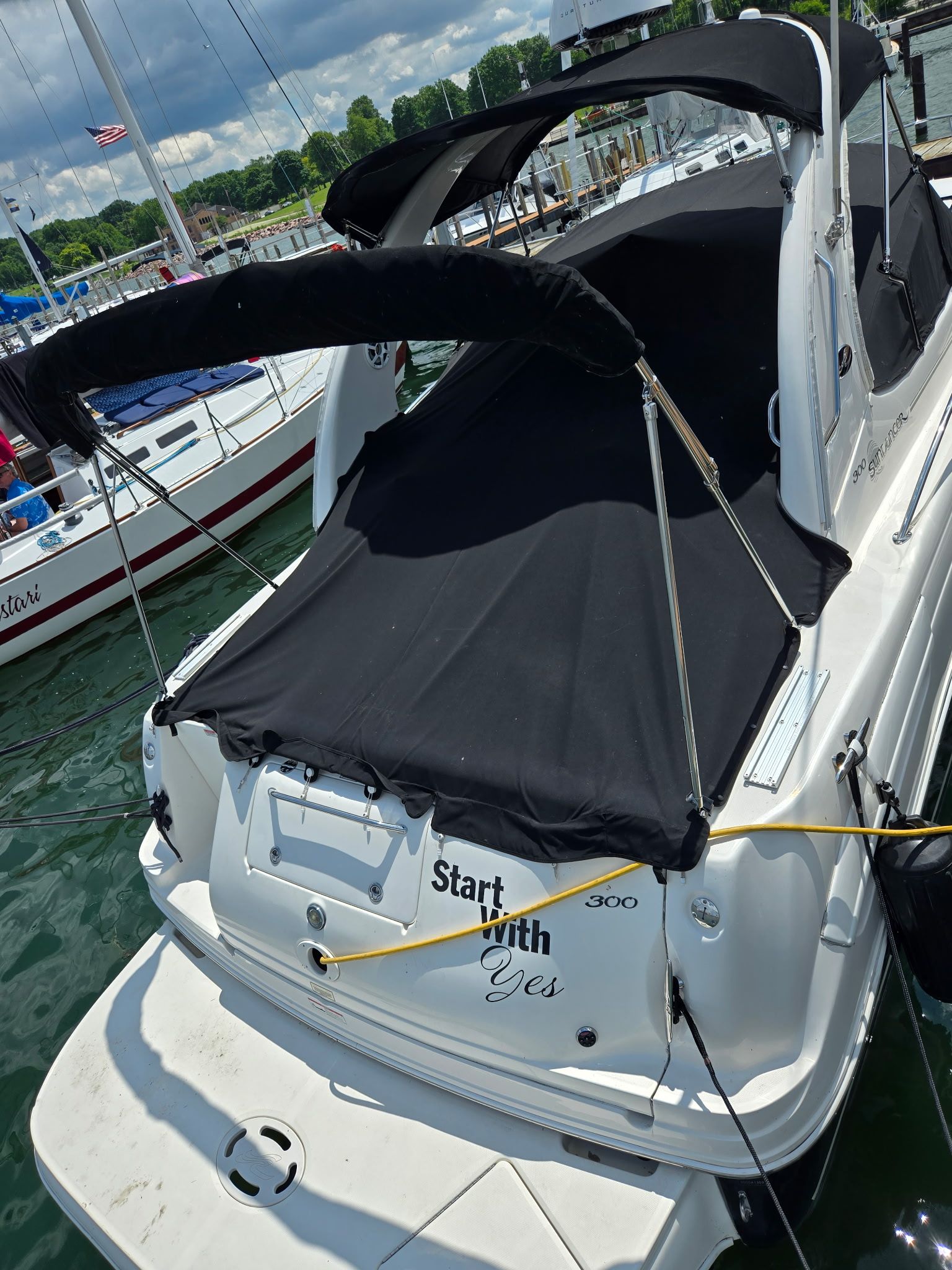 A 2006 Sea Ray 300 Sundancer in the water, featuring a black cover and 'Start with Yes' text.