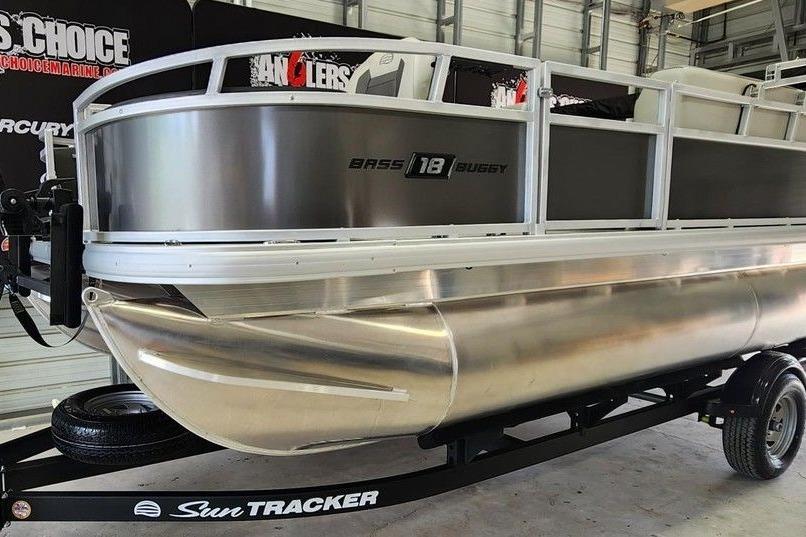 2026 Sun Tracker Bass Buggy 18 DLX pontoon boat on trailer in showroom.