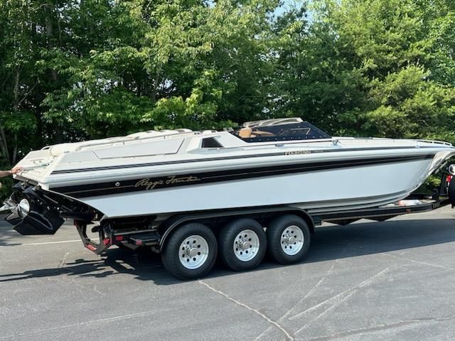 1992 Fountain Fever boat on trailer, parked outdoors, surrounded by trees.