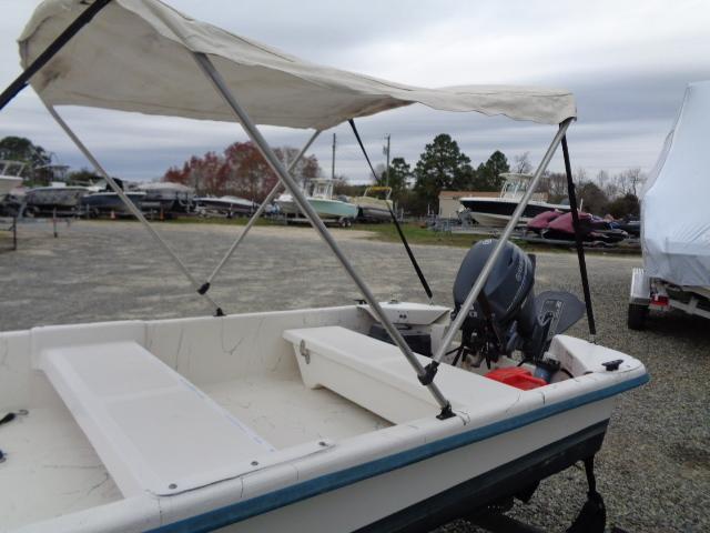 2010 Sundance K14T boat with canopy and outboard motor in a boatyard.