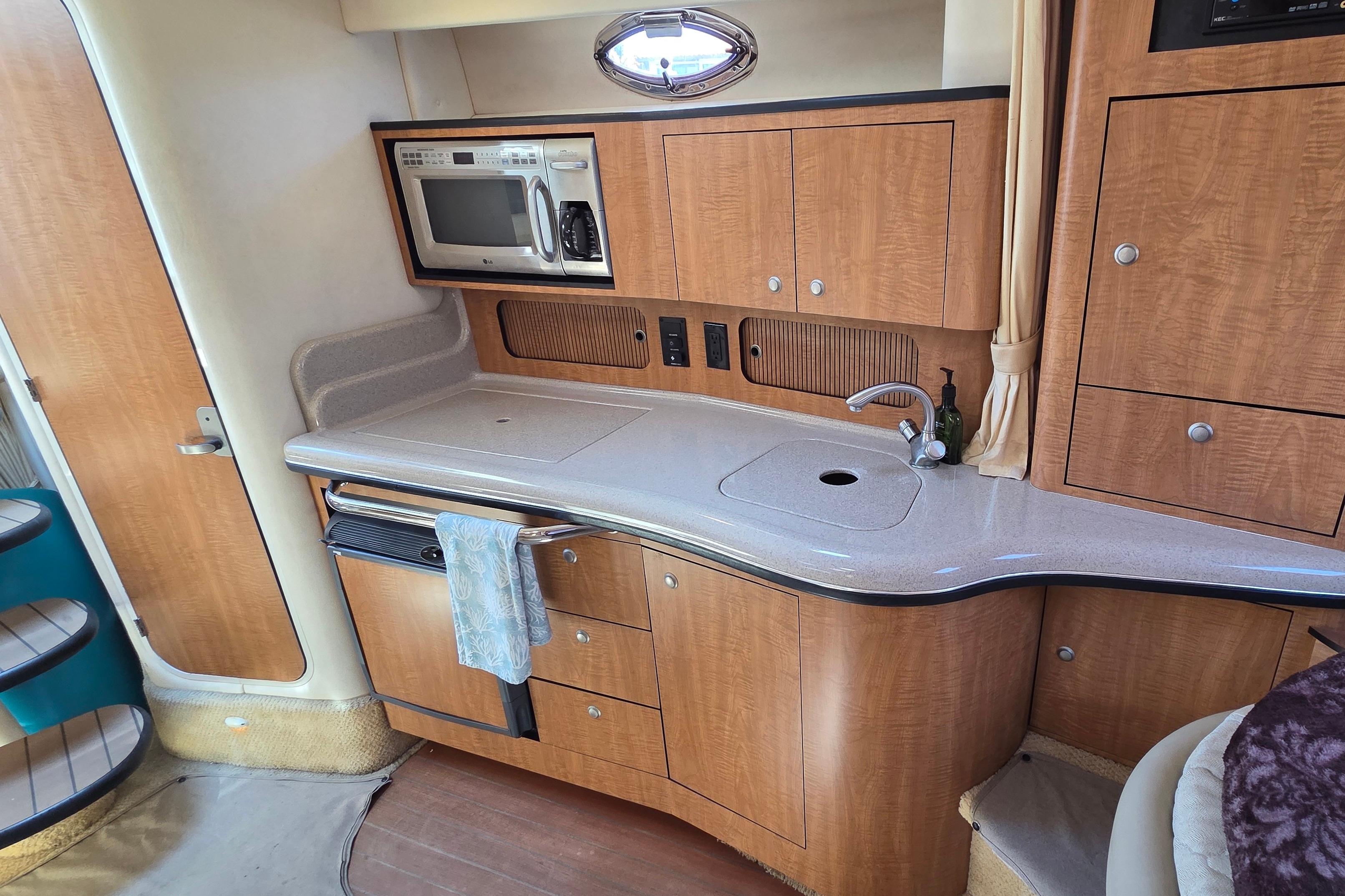 2006 Sea Ray Sundancer 320 yacht kitchen with microwave, sink, and wooden cabinetry.