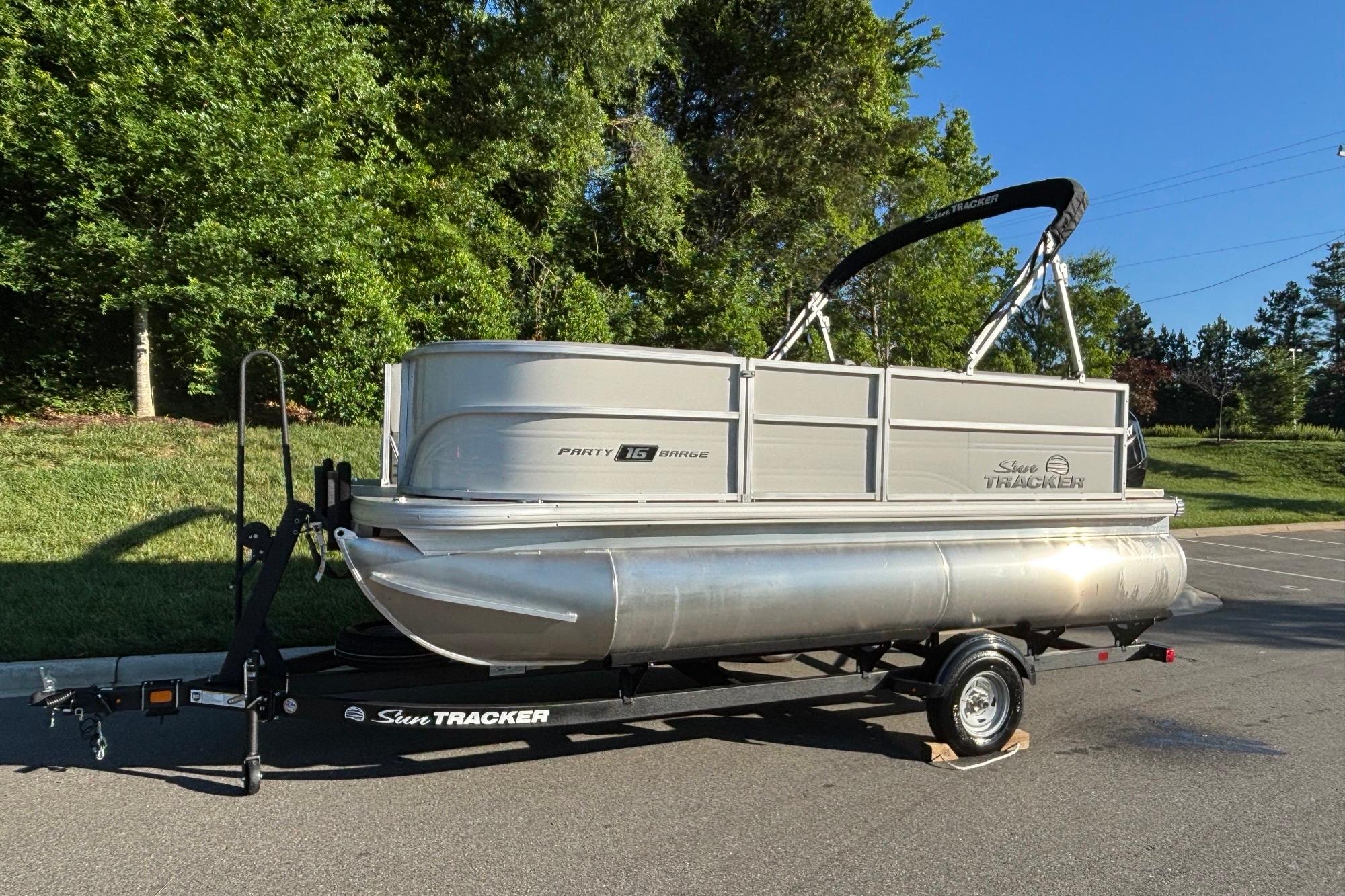 2026 Sun Tracker Party Barge 16 DLX pontoon boat on trailer, parked outdoors.