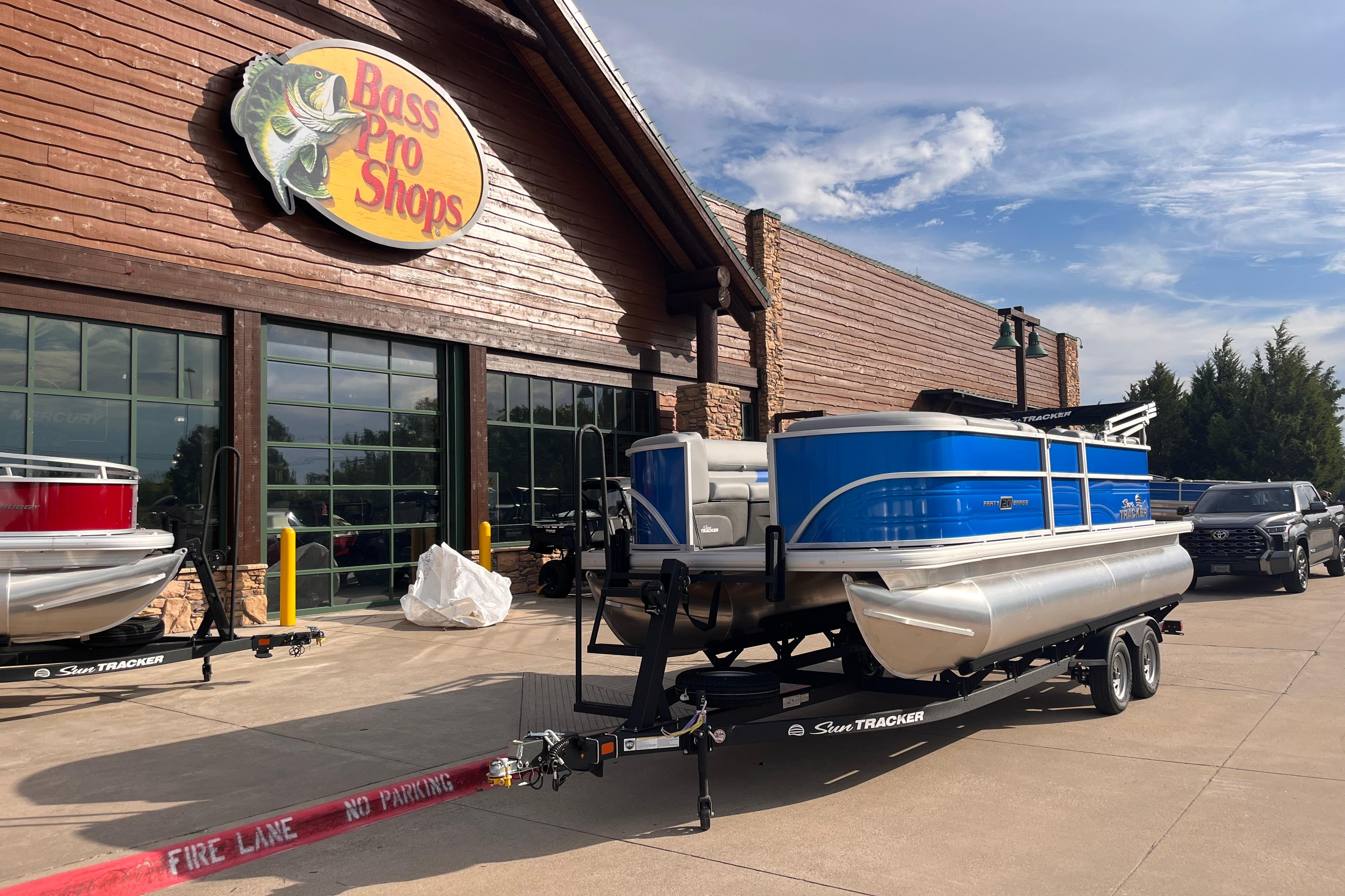 2026 Sun Tracker Party Barge 20 DLX pontoon boat at Bass Pro Shops entrance.