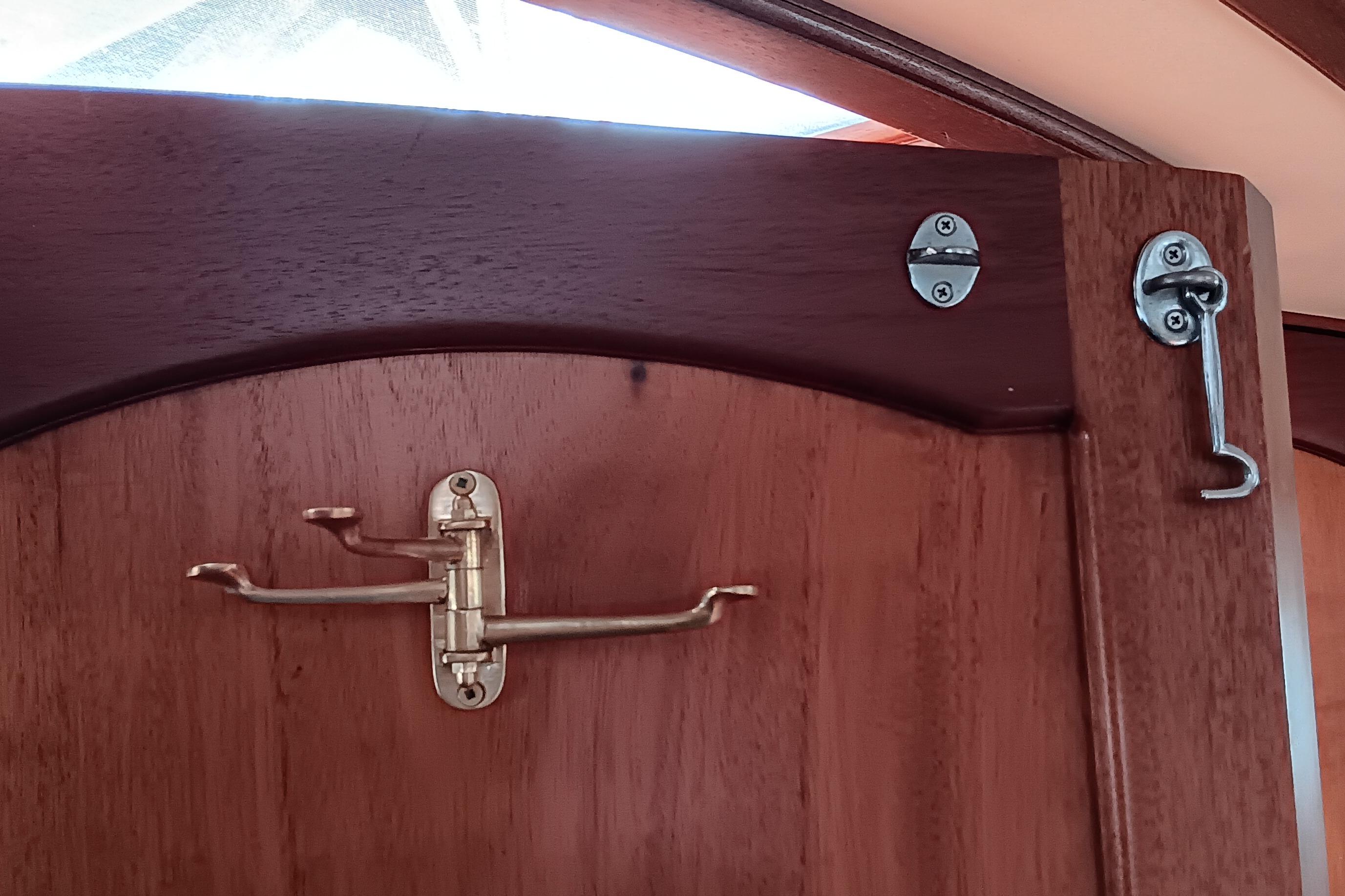 Wooden door with brass latch and hook on a 1991 Gozzard 31 boat.