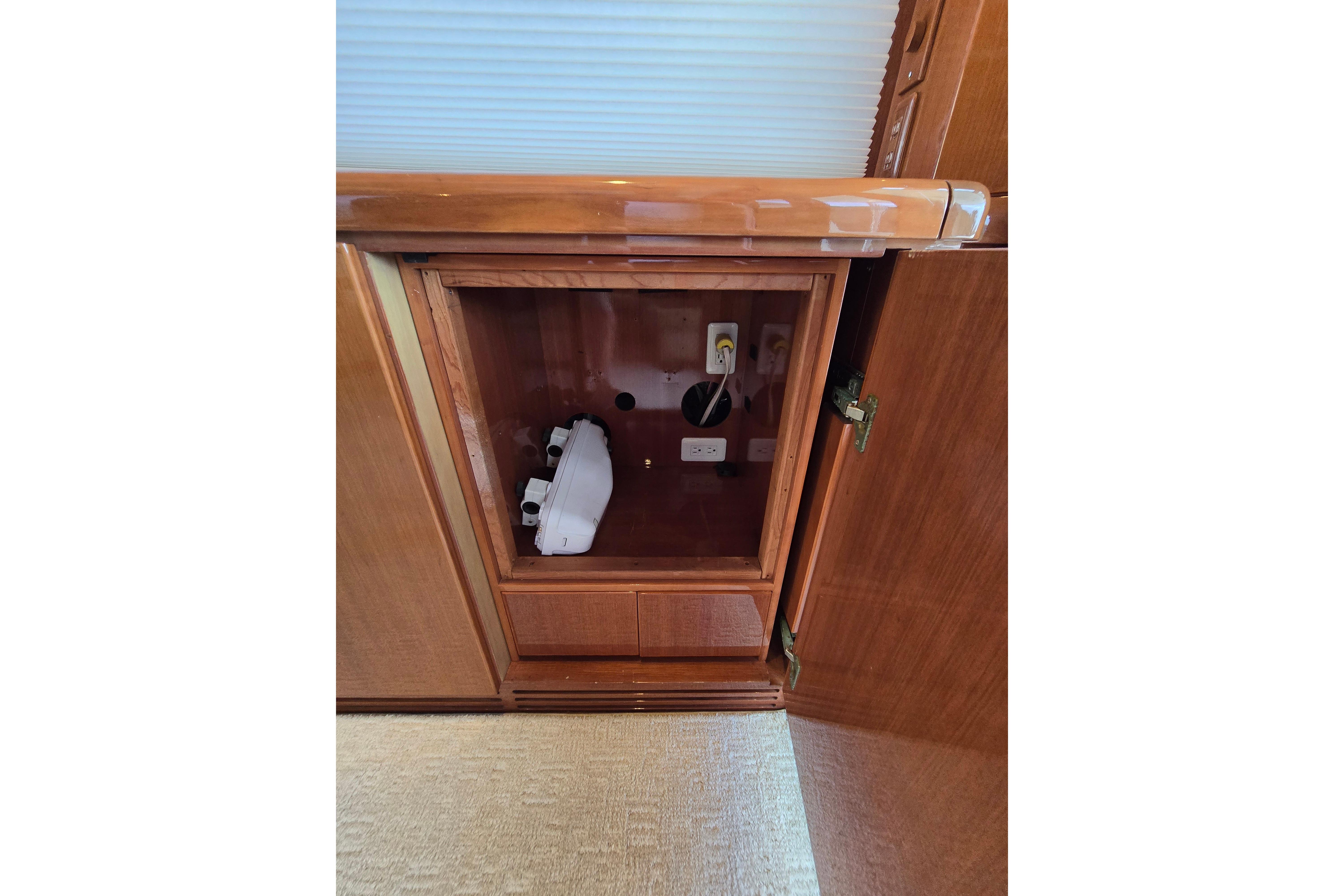 Open wooden cabinet on 2004 Grand Harbour 58 yacht, revealing electrical outlets and storage space.