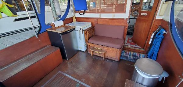 Interior of a vintage Matthews Sedan boat, featuring seating, fridge, and wooden accents.