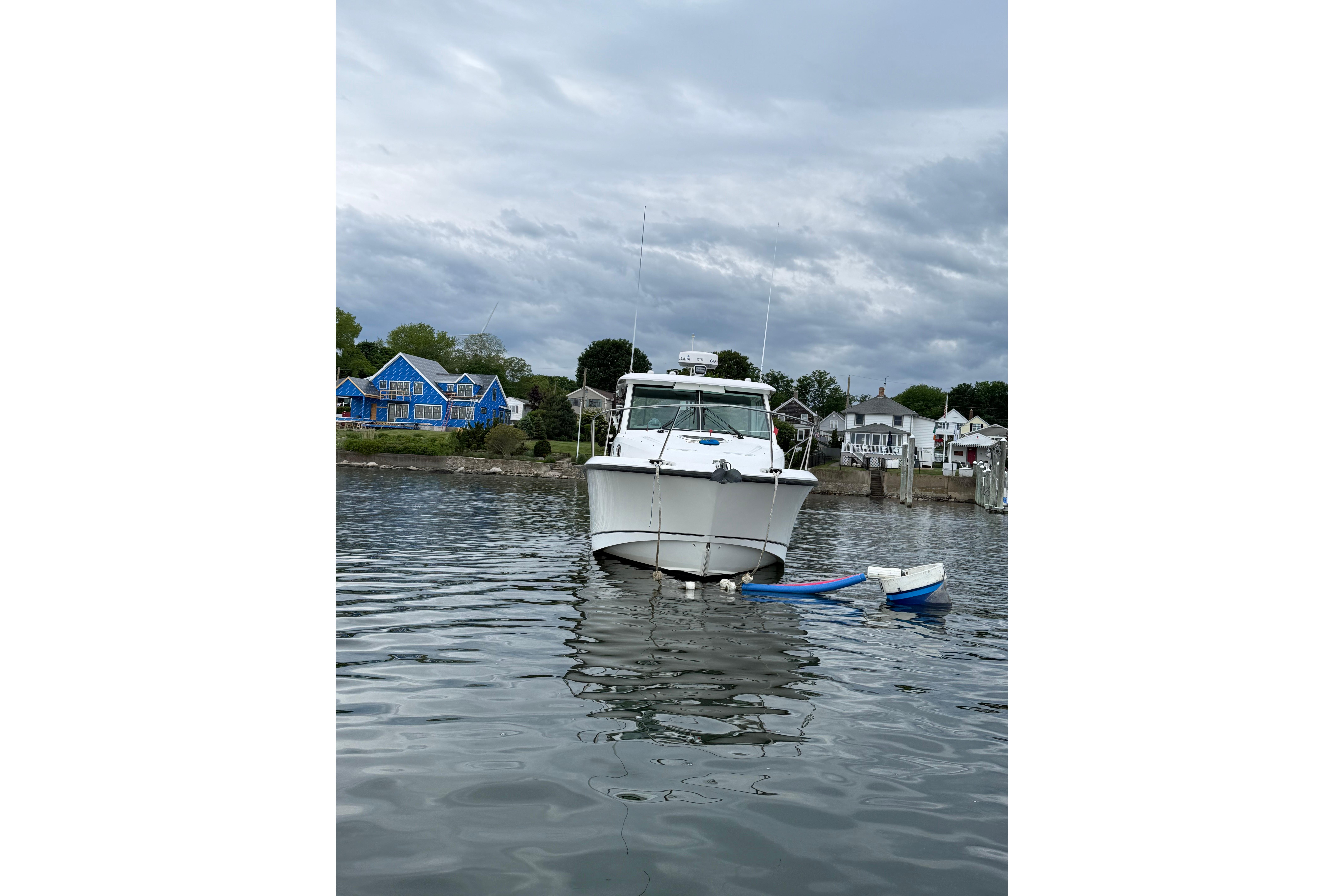 2013 Boston Whaler 315 Conquest boat on calm water near colorful houses.