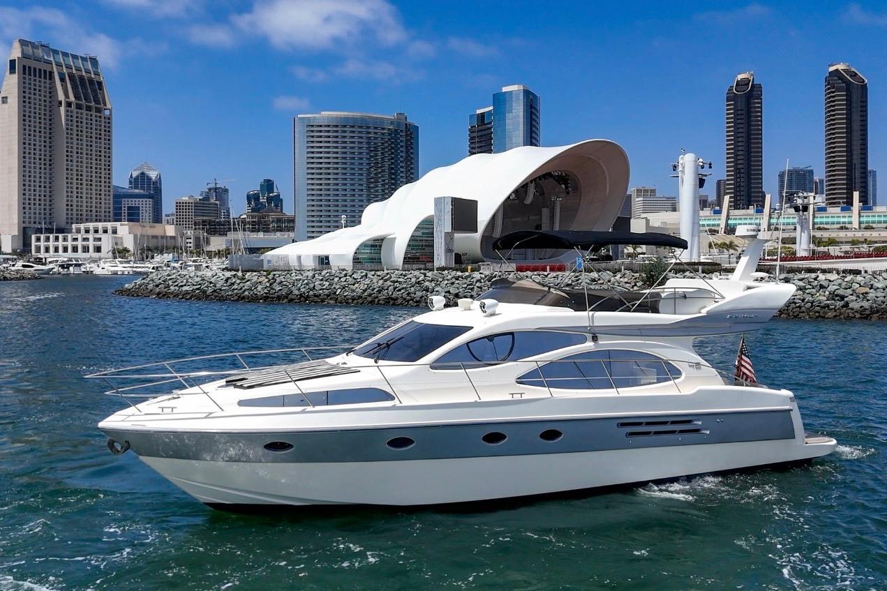 2004 Azimut 46 yacht cruising near modern city skyline and waterfront architecture.