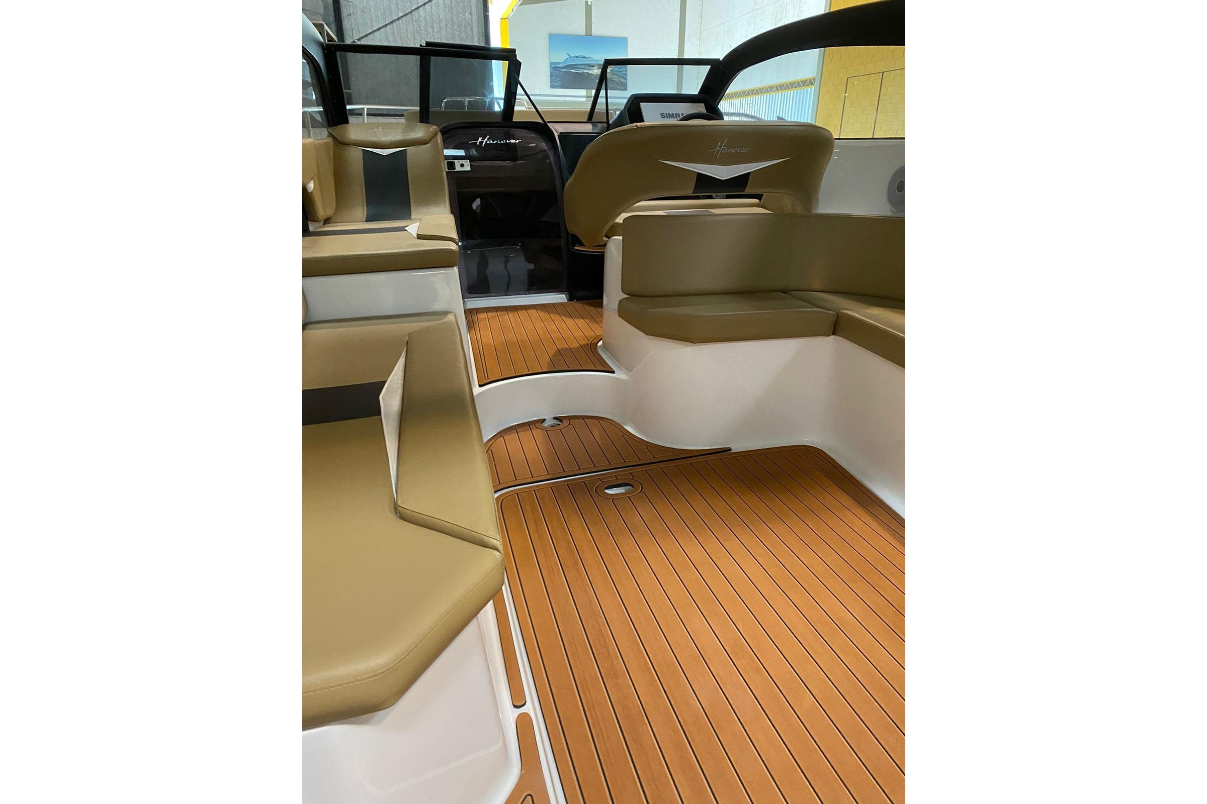 Interior of 2026 Hanover 305 boat with tan seating and wood-style flooring.