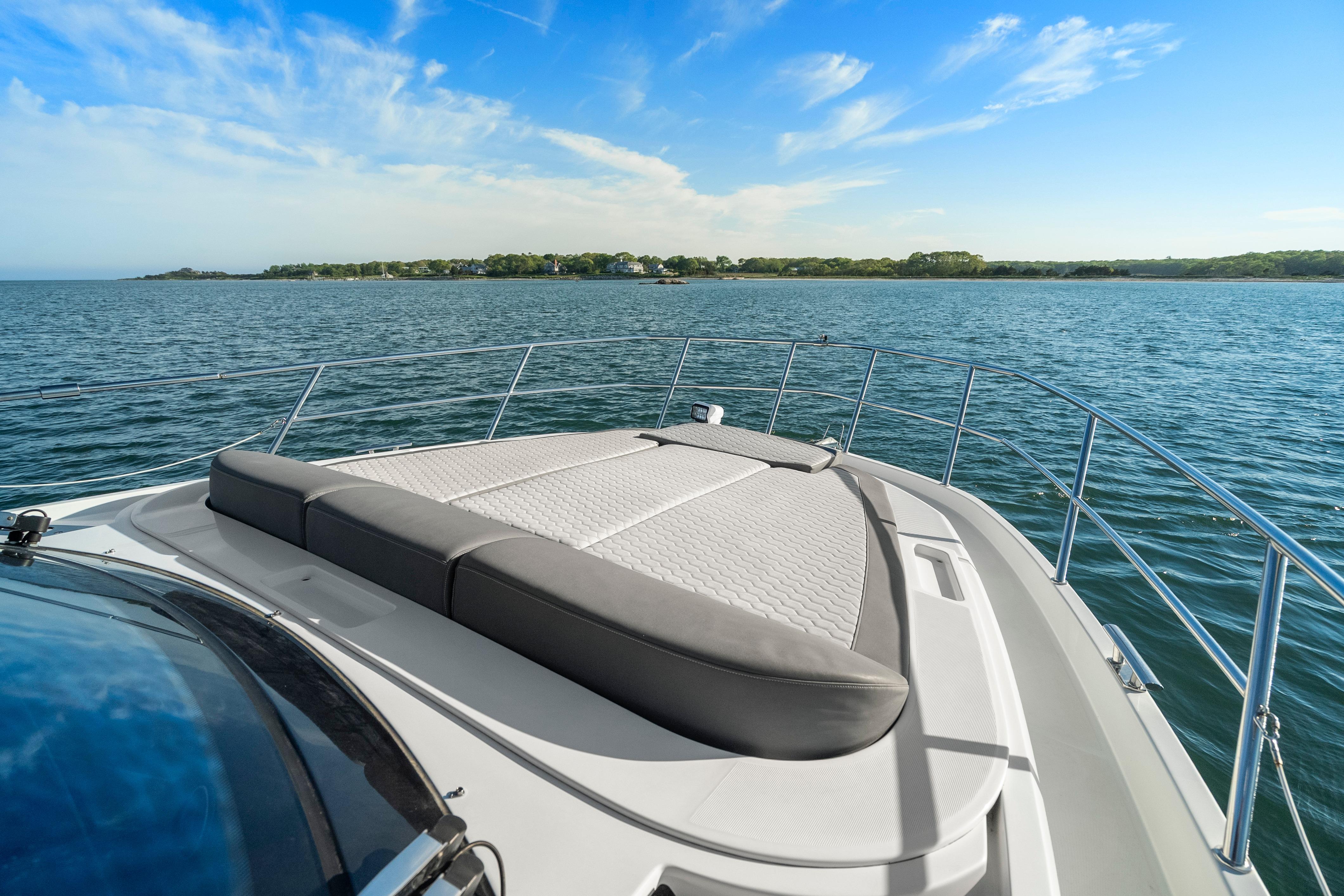 2023 Galeon 400 Fly yacht with sunbed, cruising on serene waters under a clear blue sky.