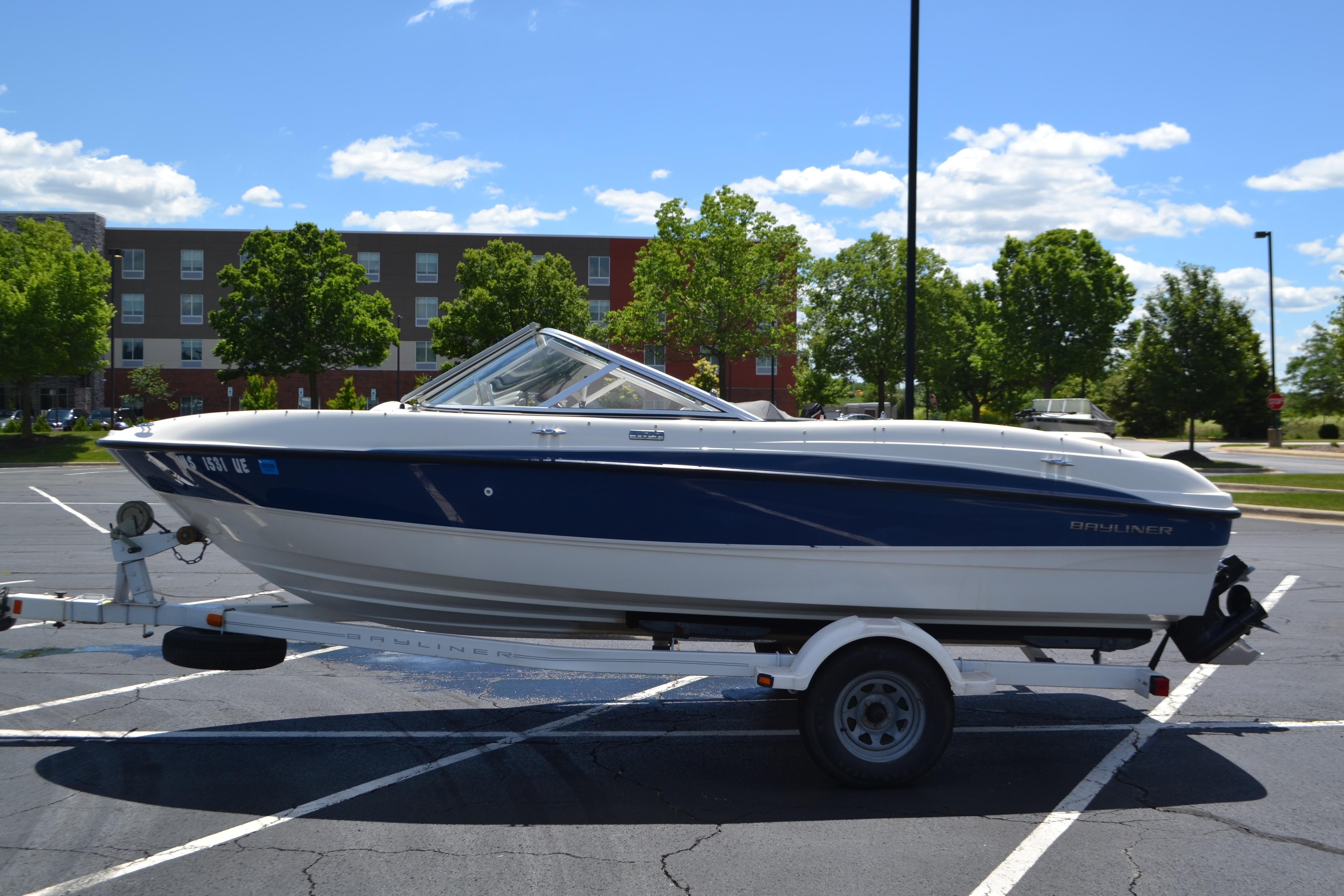 2009 Bayliner 185 Bowrider boat on trailer in sunny parking lot.