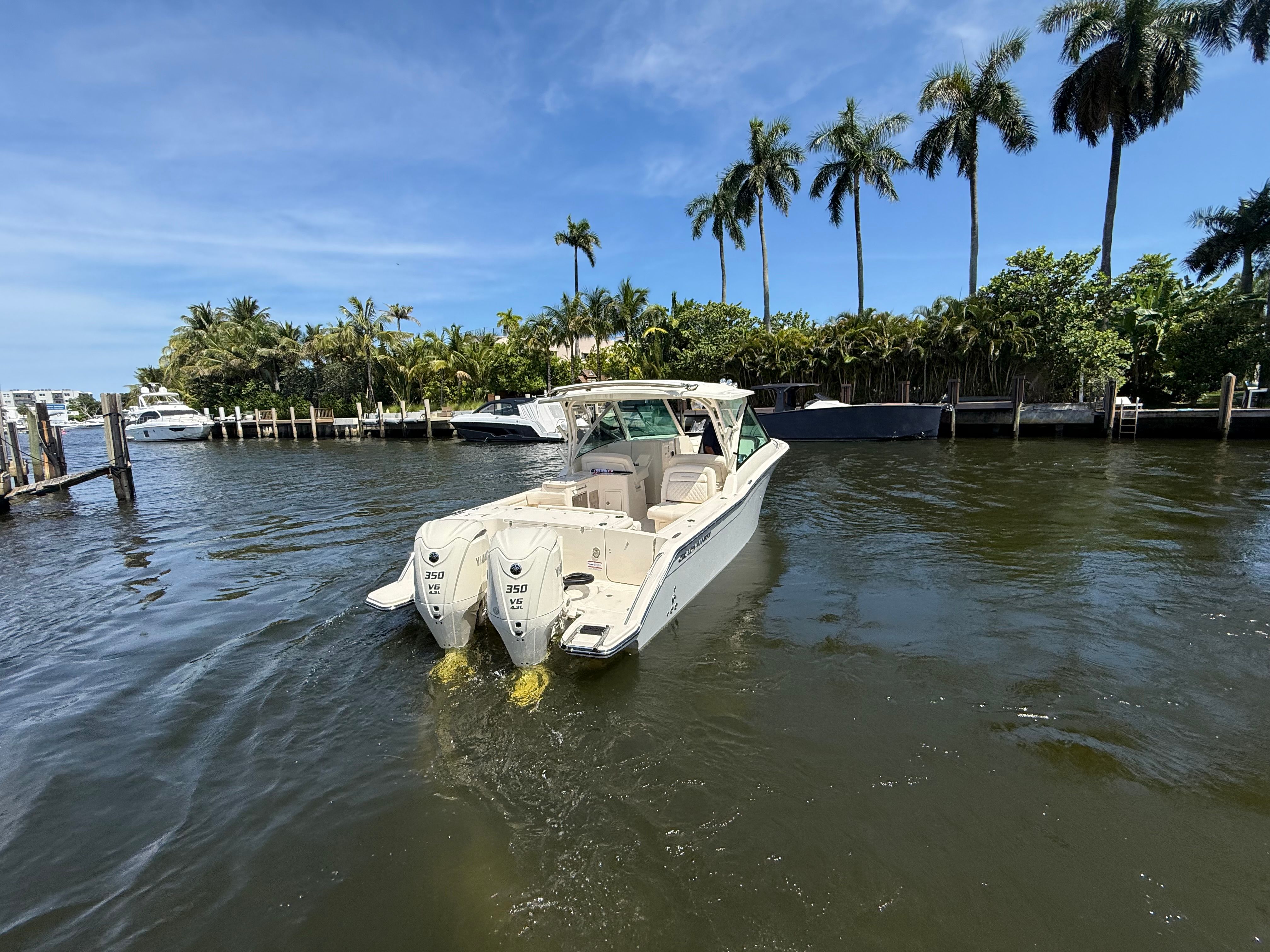 A Grady-White Freedom 325 boat on calm water, surrounded by palm trees.