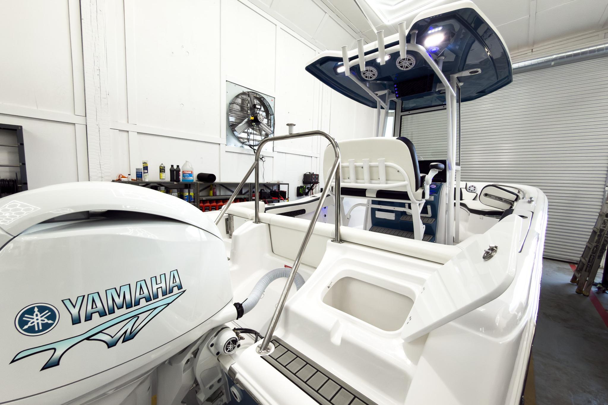 The image shows a modern boat with a Yamaha engine in a workshop.