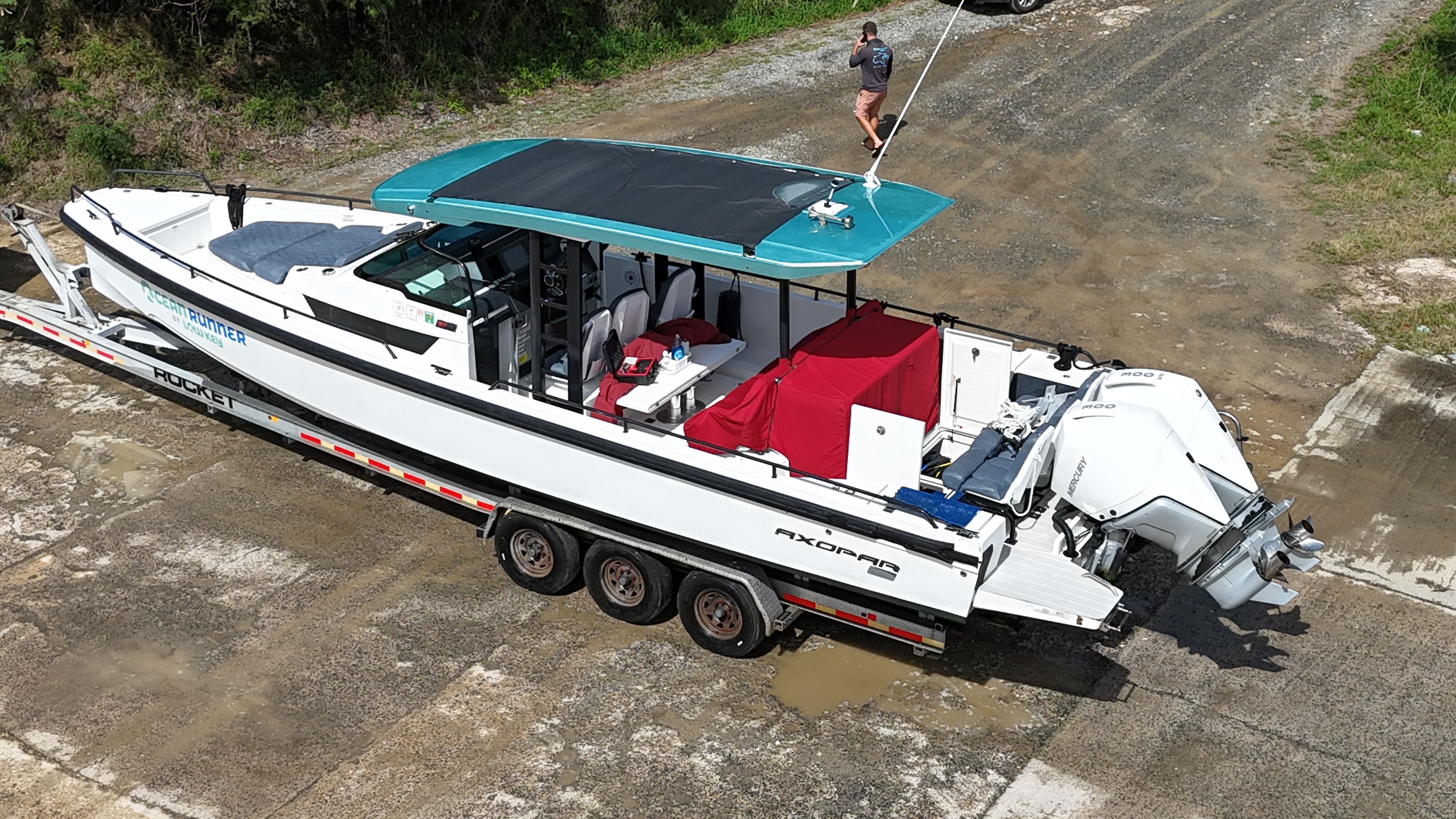 A 2020 Axopar 37 SUN TOP on a trailer, featuring a blue roof and red seating.