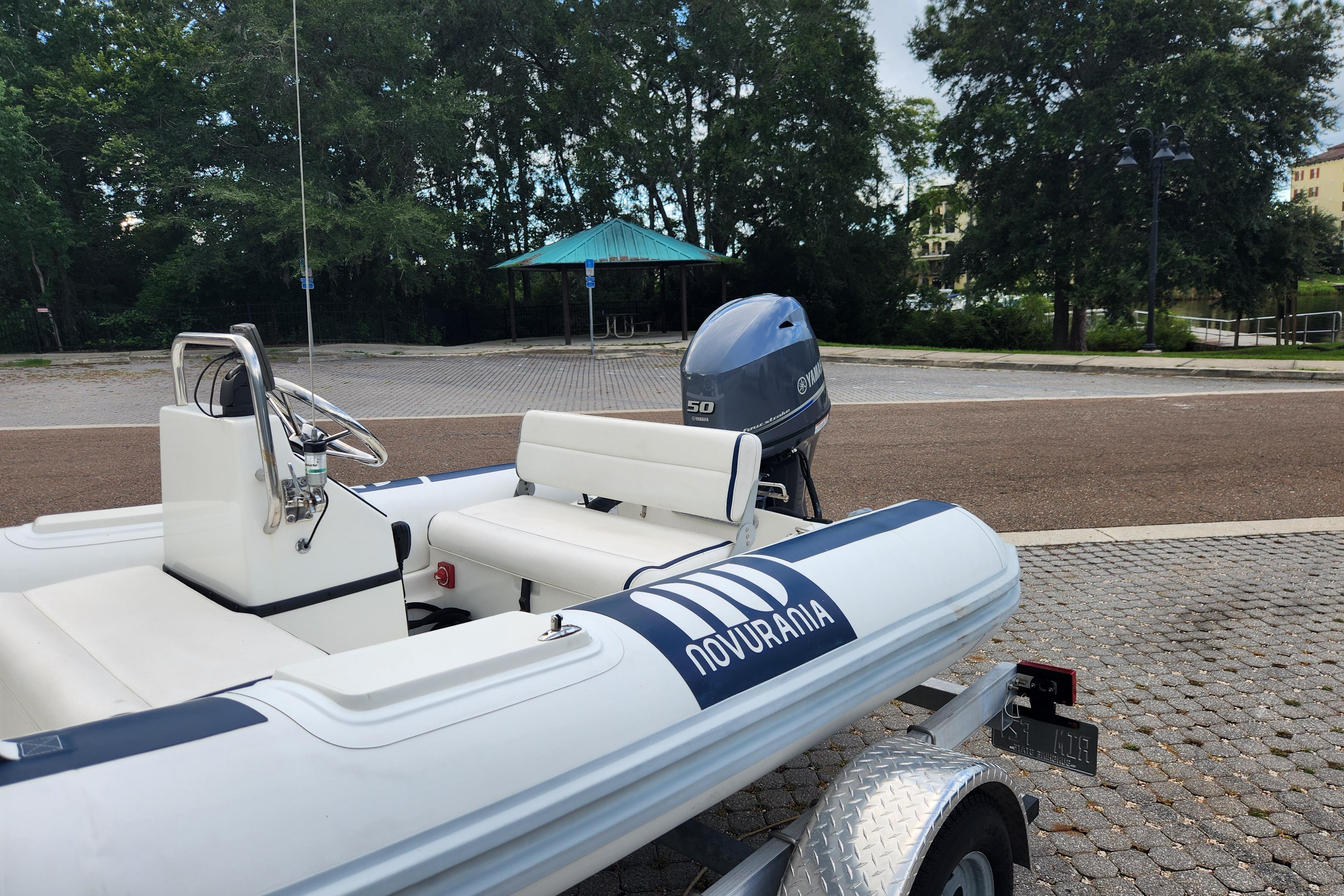 2019 Novurania DL 400 boat on trailer, parked near trees and pavilion.
