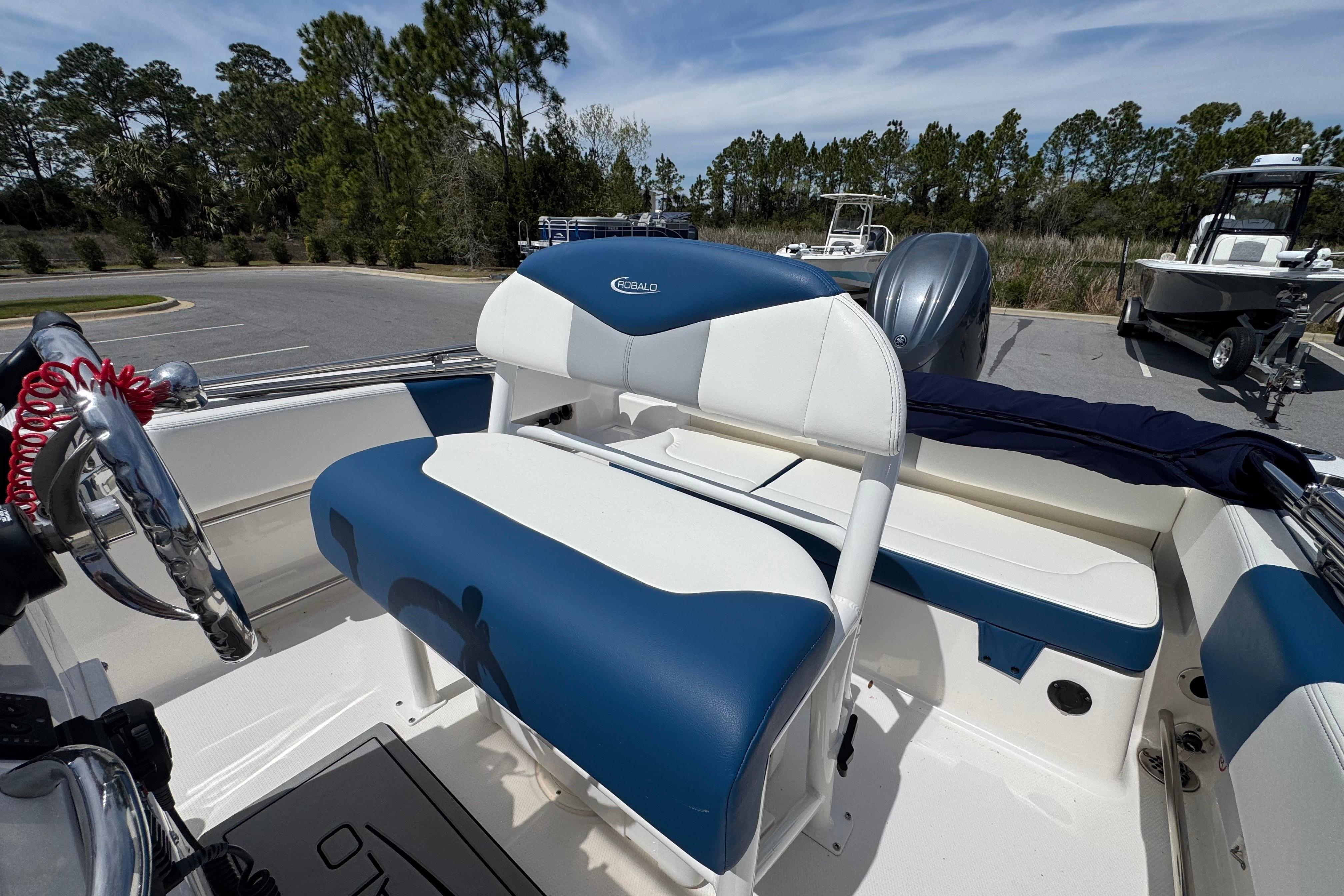 2023 Robalo R202 Explorer boat interior with blue and white seating, steering wheel, and outboard motor.