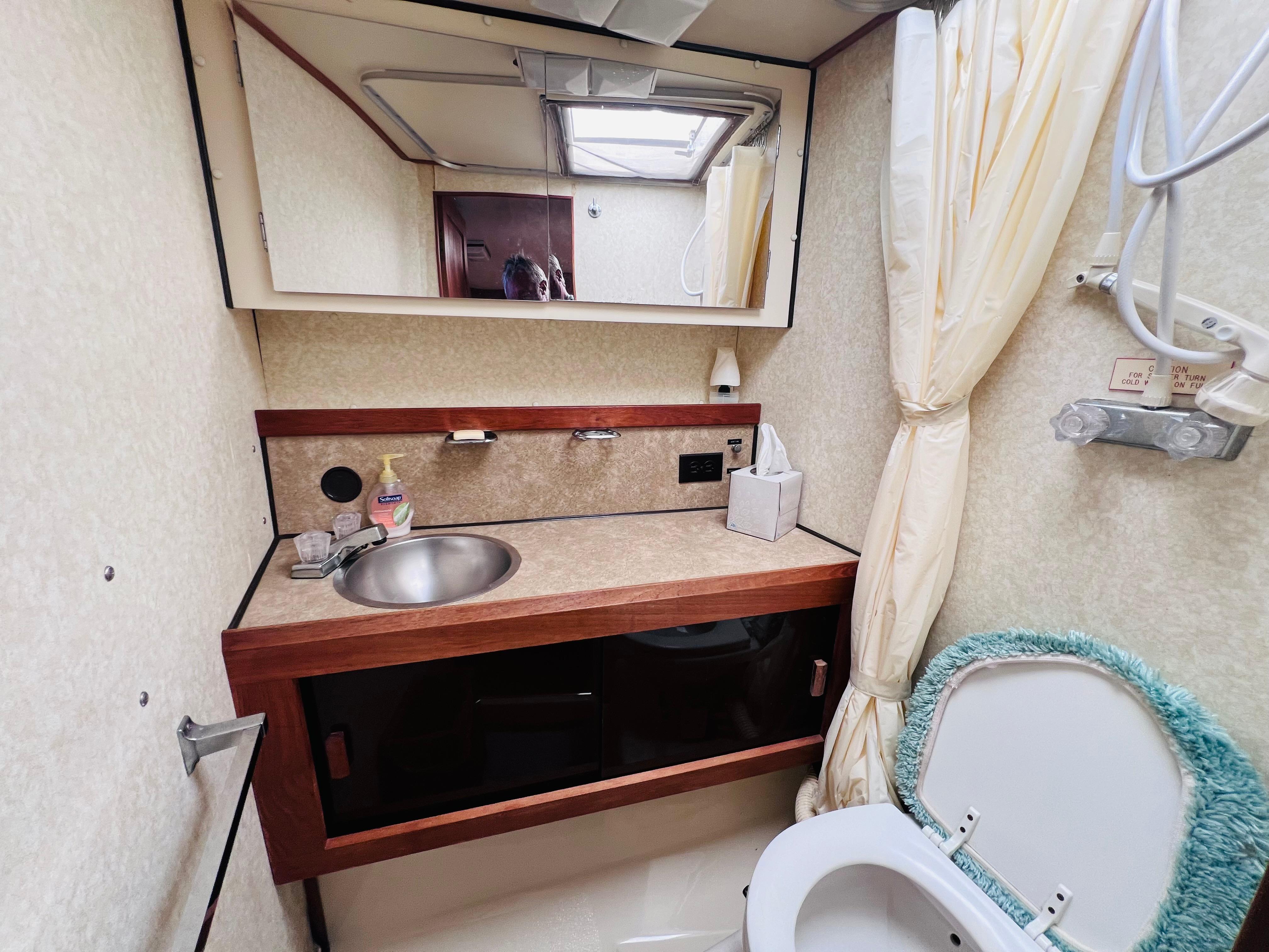 1982 Trojan F32 boat bathroom with sink, mirror, and toilet.