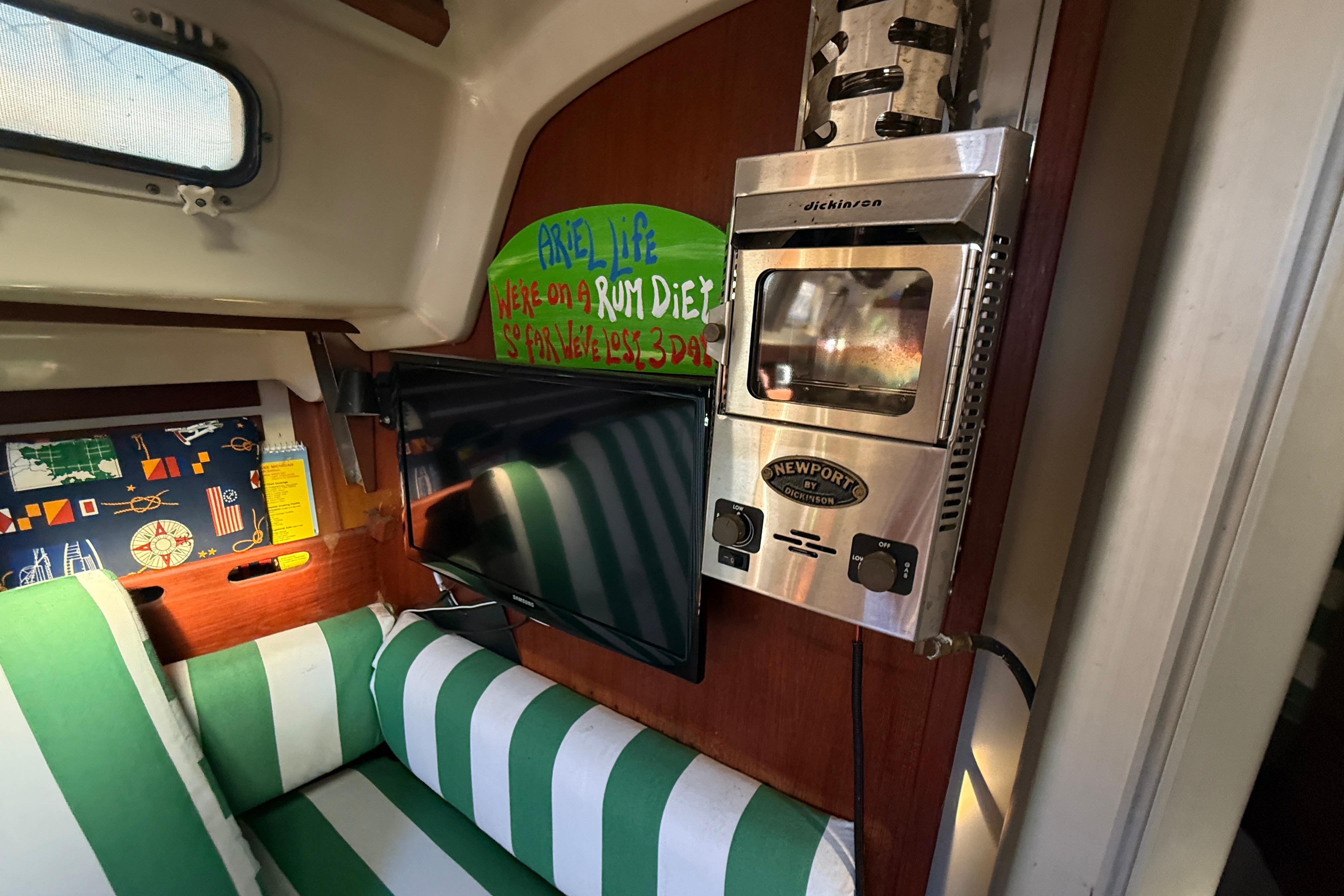 Interior of 1983 O'Day 34 sailboat with striped seating, wall art, and a Newport heater.
