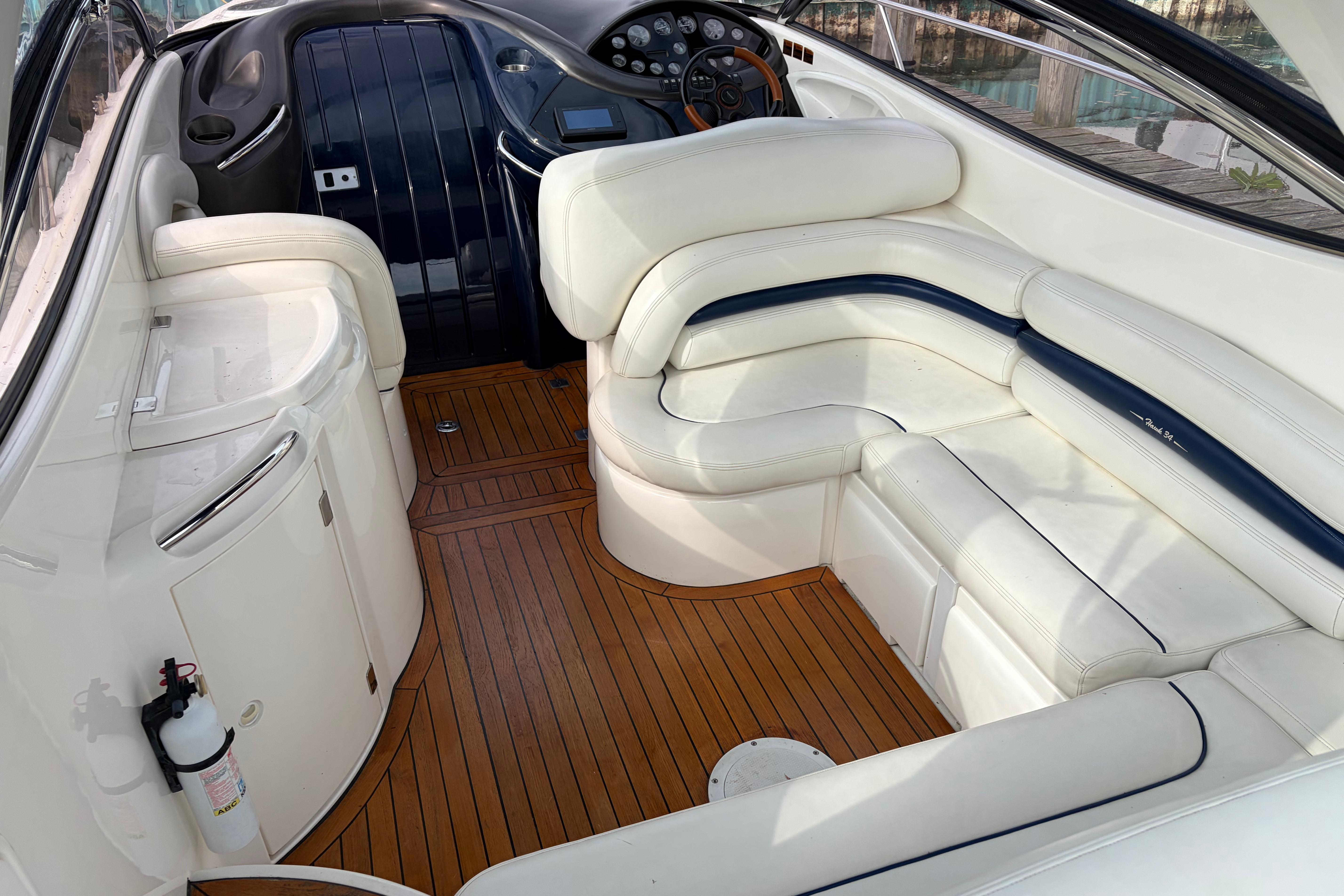 Interior of 2000 Sunseeker Superhawk 34 yacht with white seating and wooden flooring.