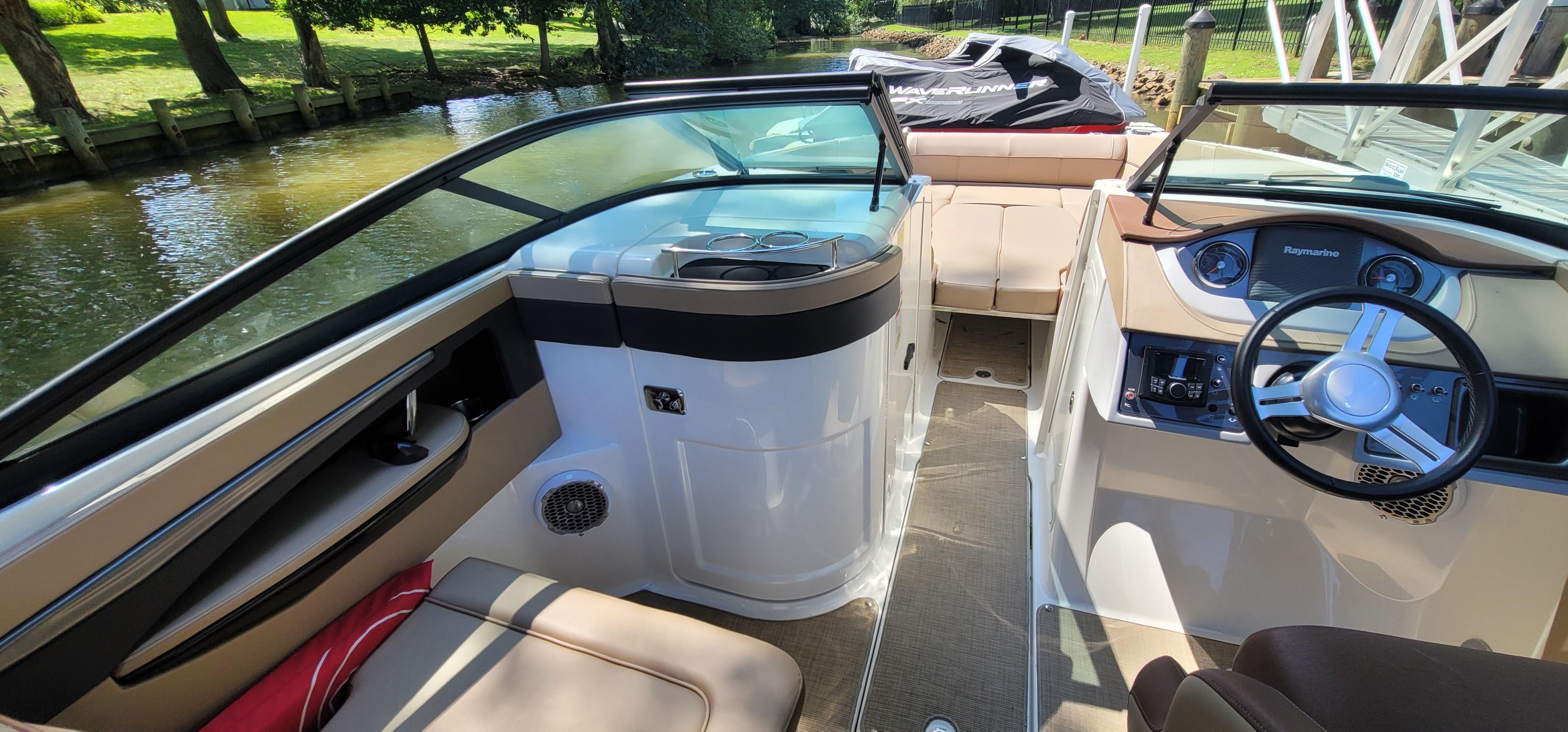 2017 Sea Ray SDX 240 Outboard interior with steering wheel and seating, docked by a scenic canal.