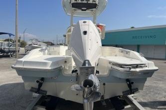 2024 Boston Whaler 220 Dauntless boat, rear view, in a marina setting.