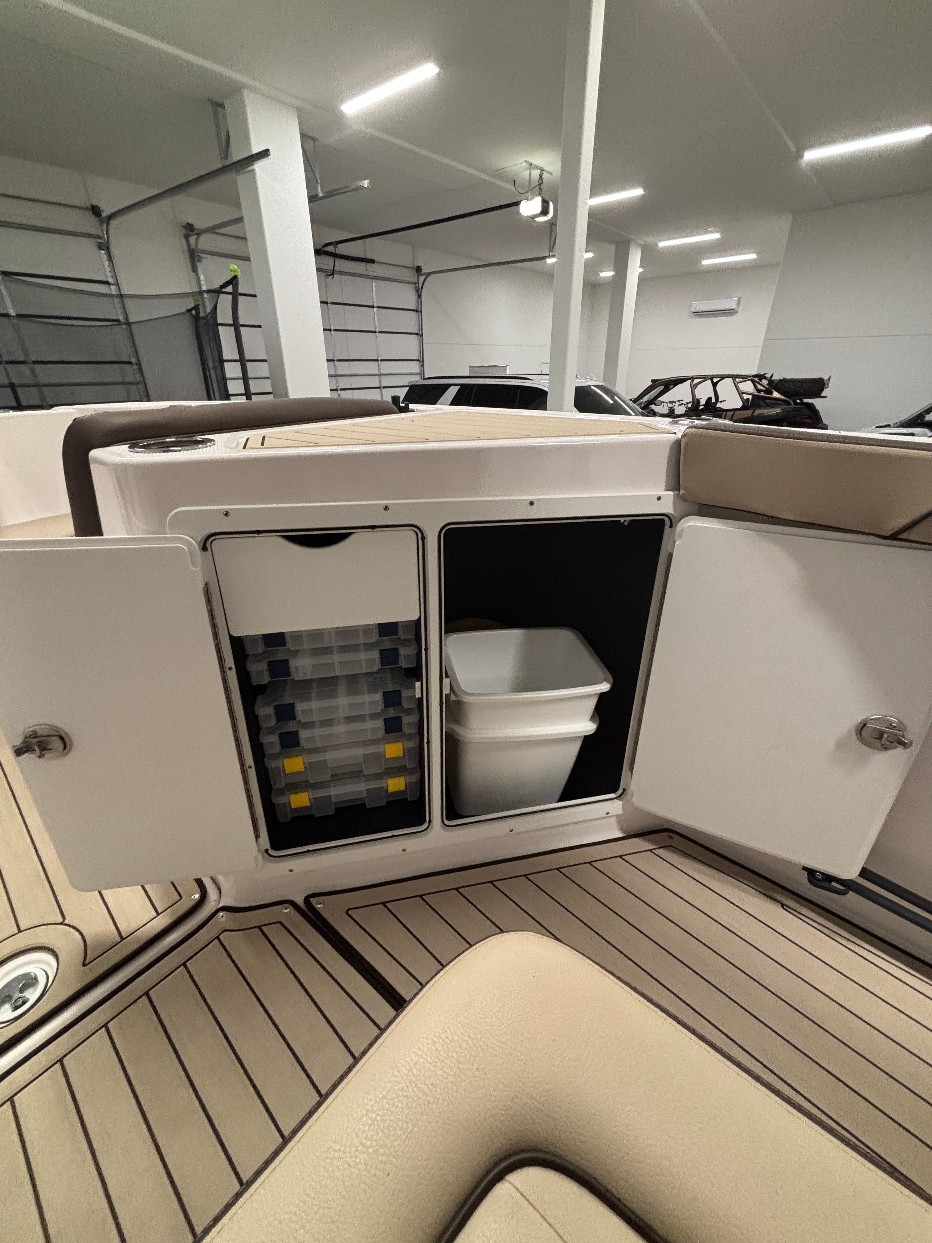 Interior view of a Yamaha 222 FSH Sport E boat with storage compartments and a trash bin.