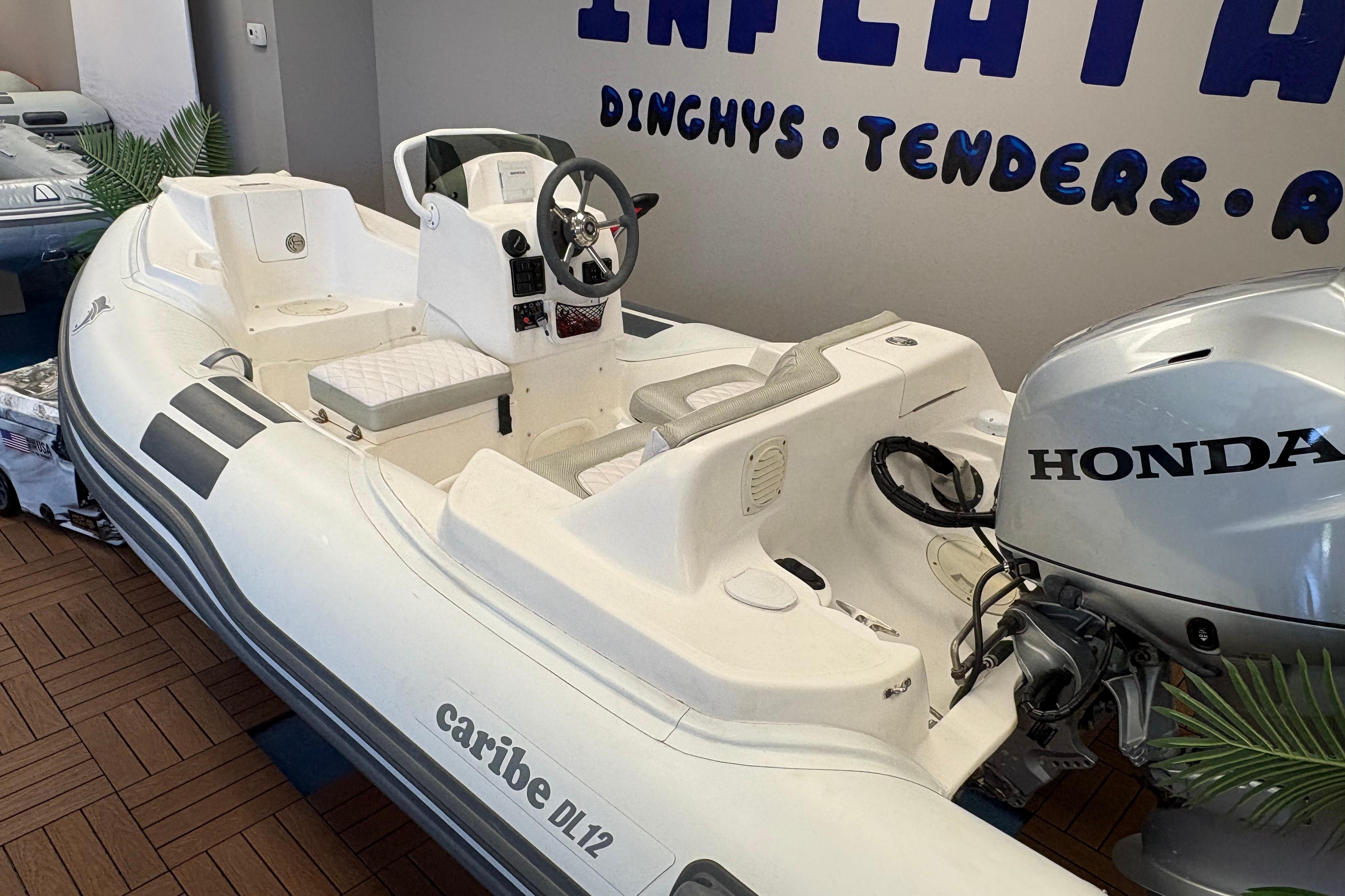 2019 Caribe DL12 inflatable boat with Honda outboard motor displayed indoors.