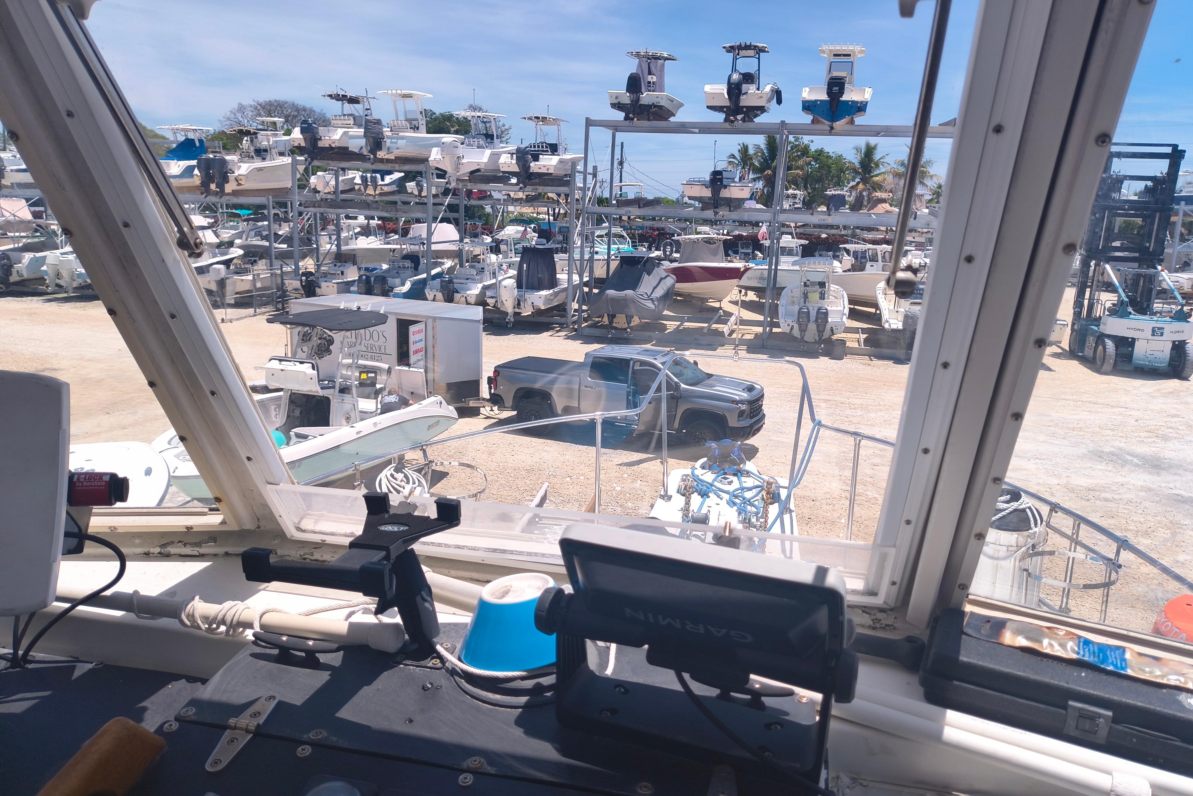 View from 1984 Kadey-Krogen Manatee boat, overlooking marina with parked boats and vehicles.