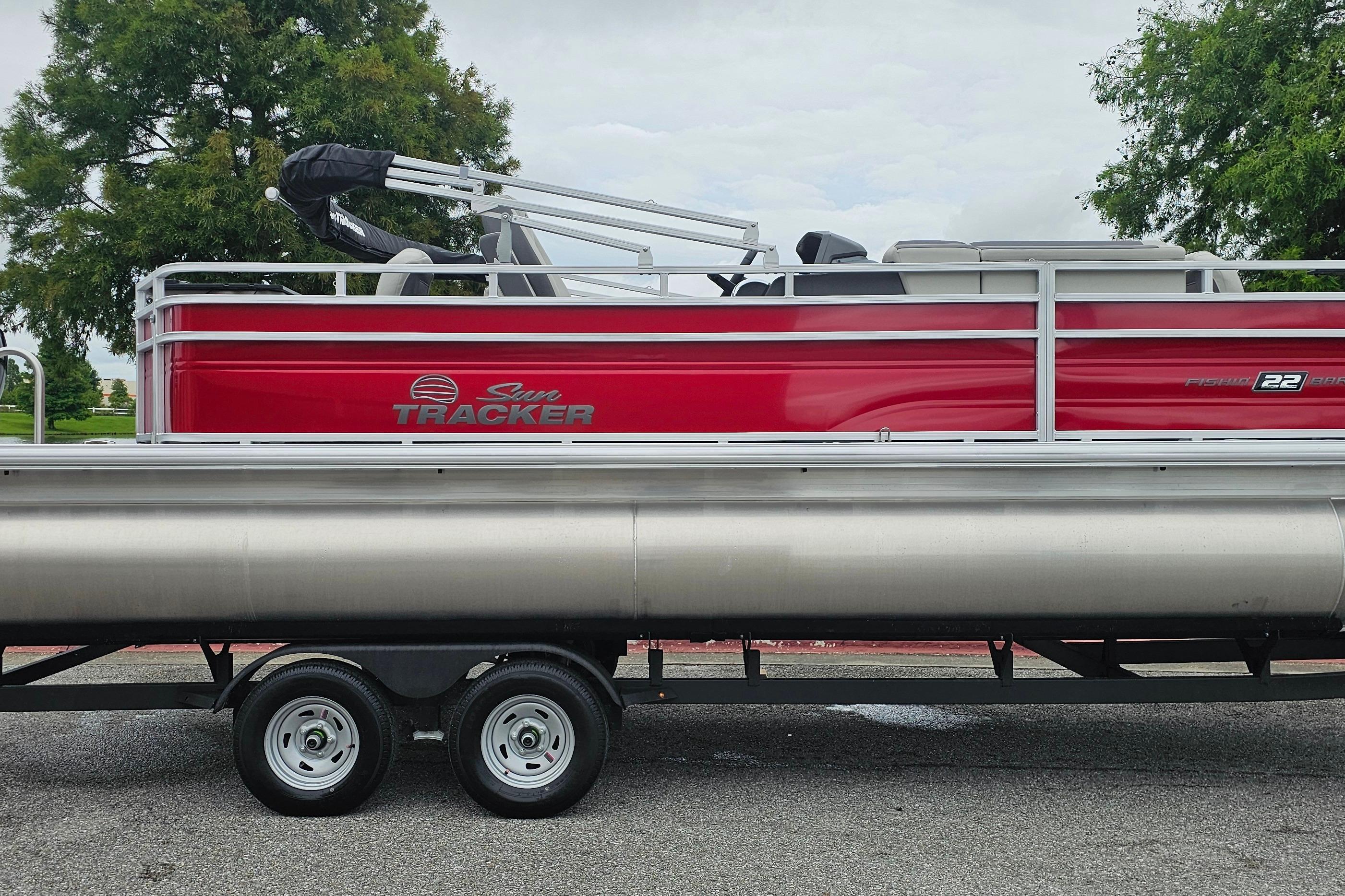 2026 Sun Tracker Fishin' Barge 22 DLX pontoon boat on trailer, side view.