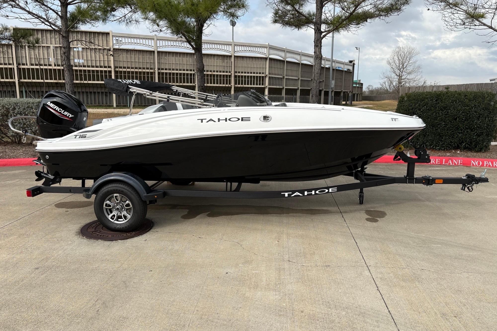 2025 Tahoe T16 boat on trailer, parked outdoors, featuring sleek black and white design.