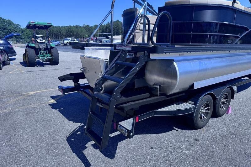 2027 Manitou Aurora 23 RF SHP pontoon boat on trailer in parking lot.
