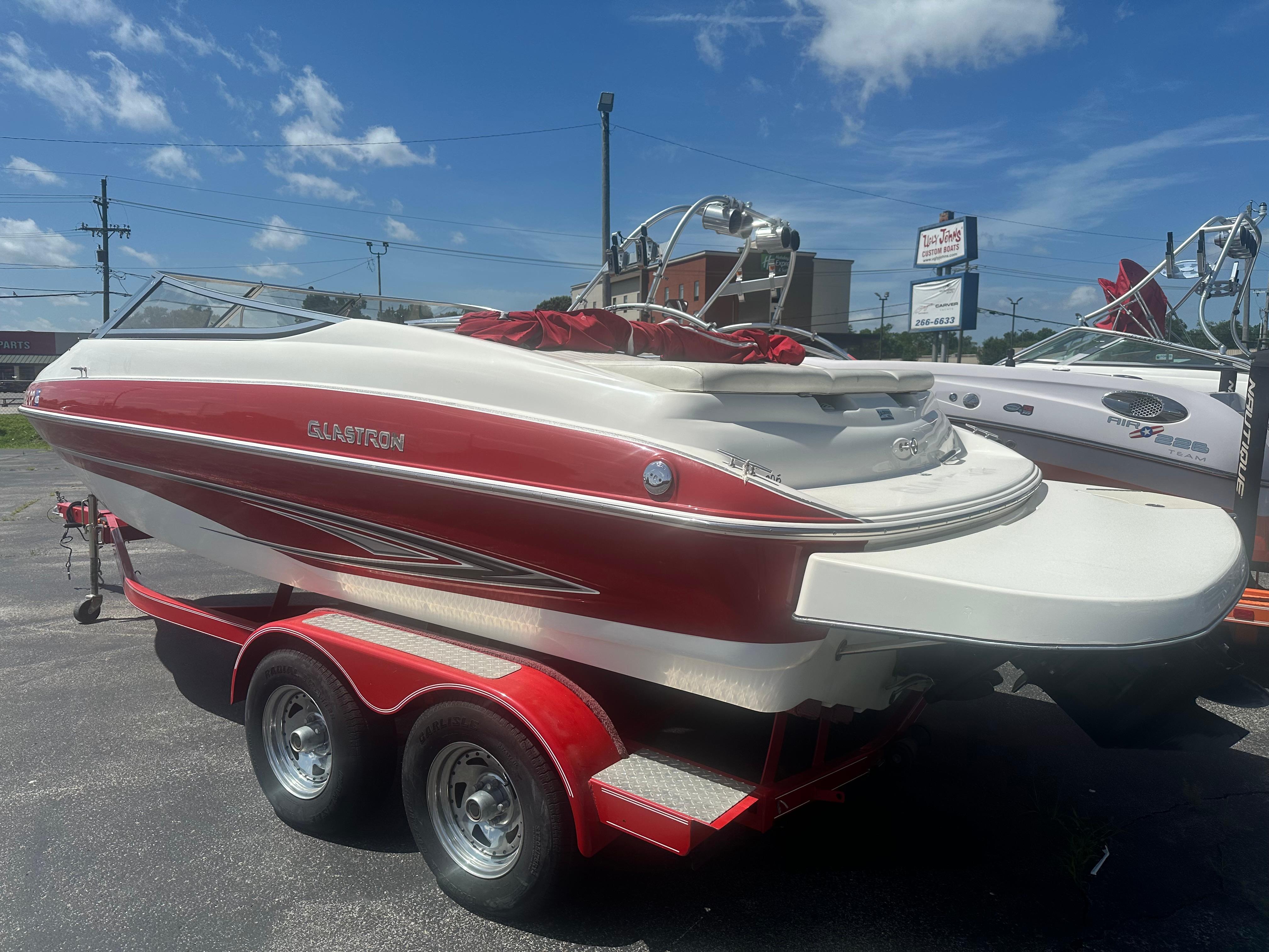2008 Glastron 205 GX boat on trailer, red and white design, parked outdoors under blue sky.