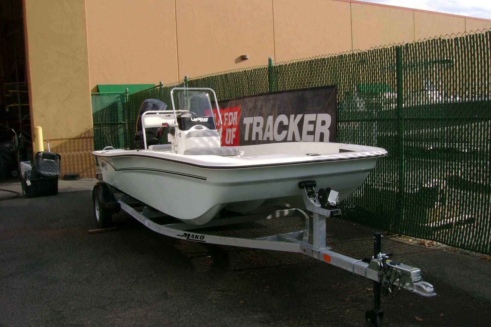 2026 Mako Pro Skiff 17 CC boat on trailer, parked near green fence.
