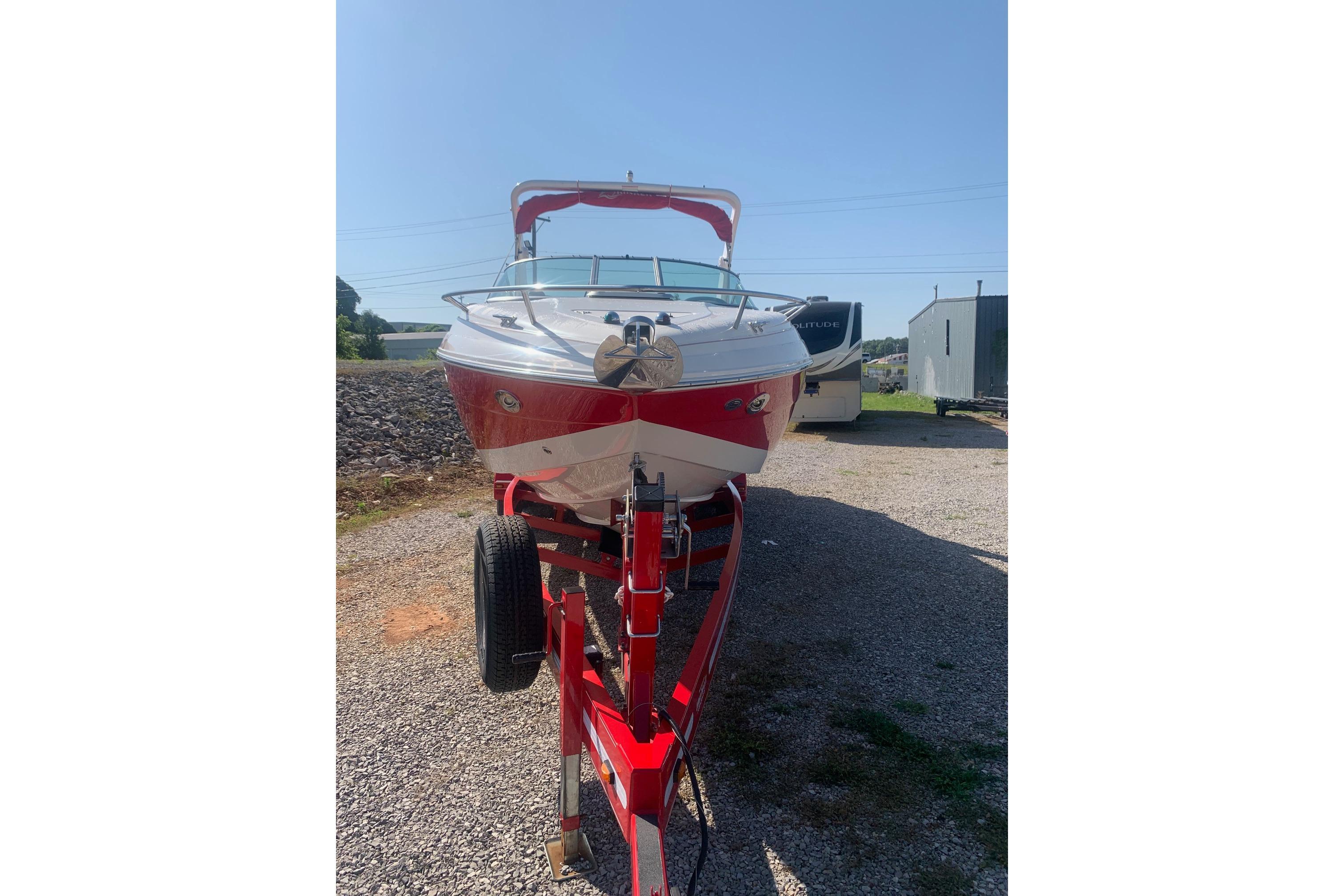 2006 Rinker 282 Captiva Cuddy boat on trailer, red and white exterior, sunny day.
