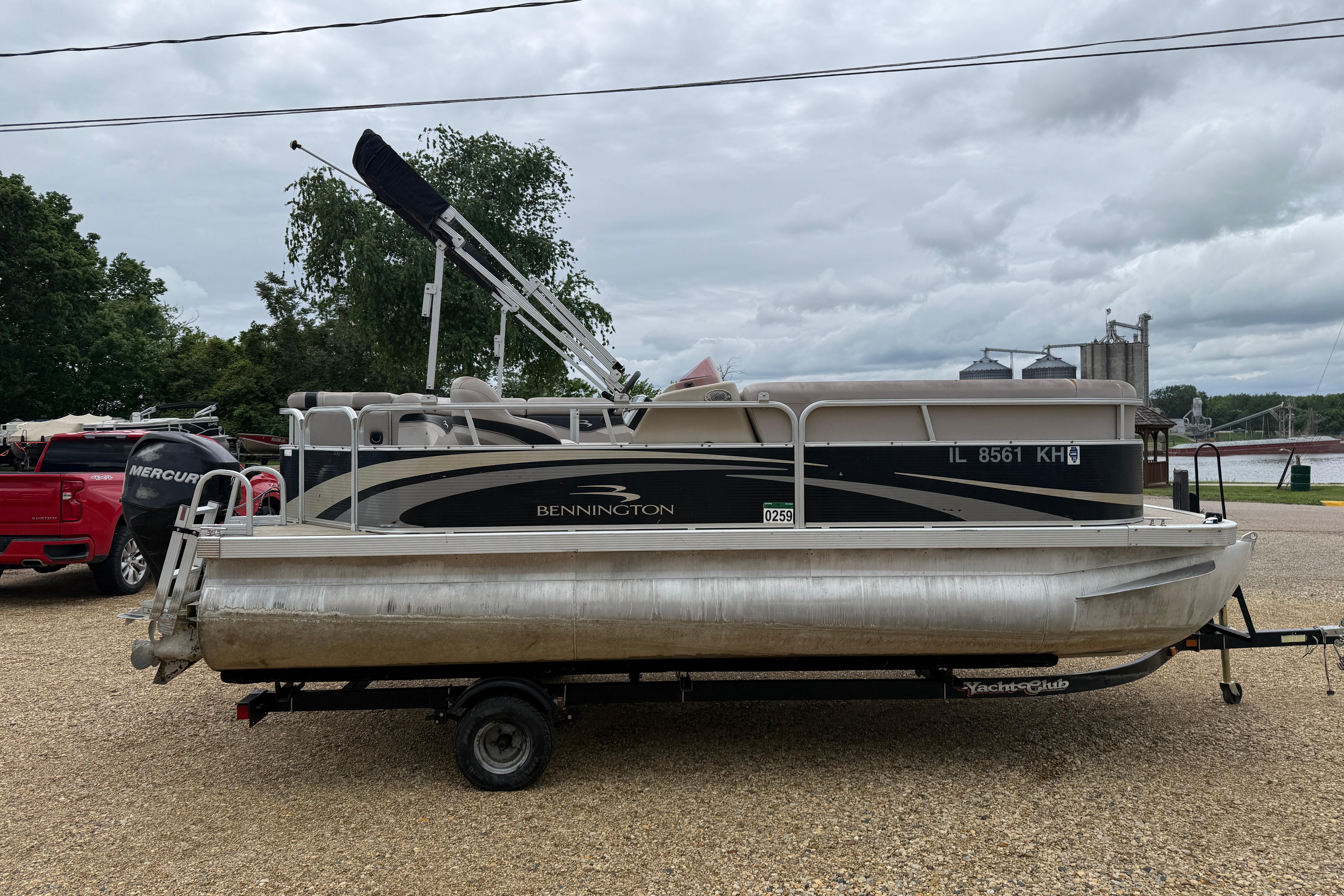 2010 Bennington 20SLi pontoon boat on trailer, parked outdoors on gravel.