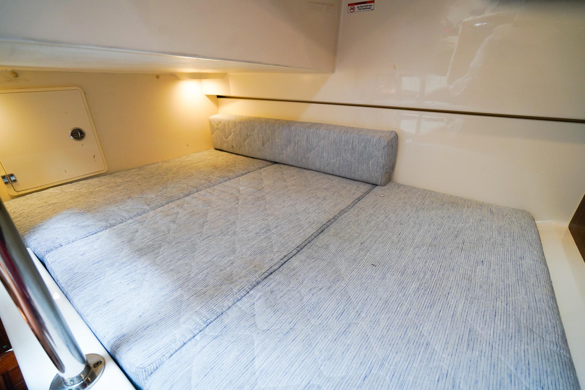 2020 Pursuit OS 325 Offshore cabin interior with cozy bedding and soft lighting.