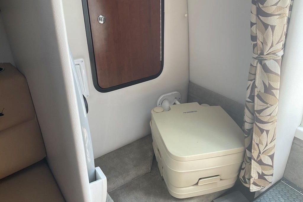 2015 Crownline 236 SC cabin interior with portable toilet and floral curtain.