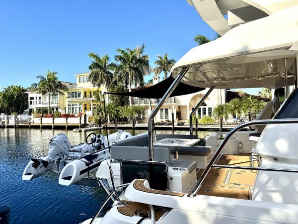 Aquila 44 yacht docked by waterfront homes, 2022 model, sunny day, palm trees in background.