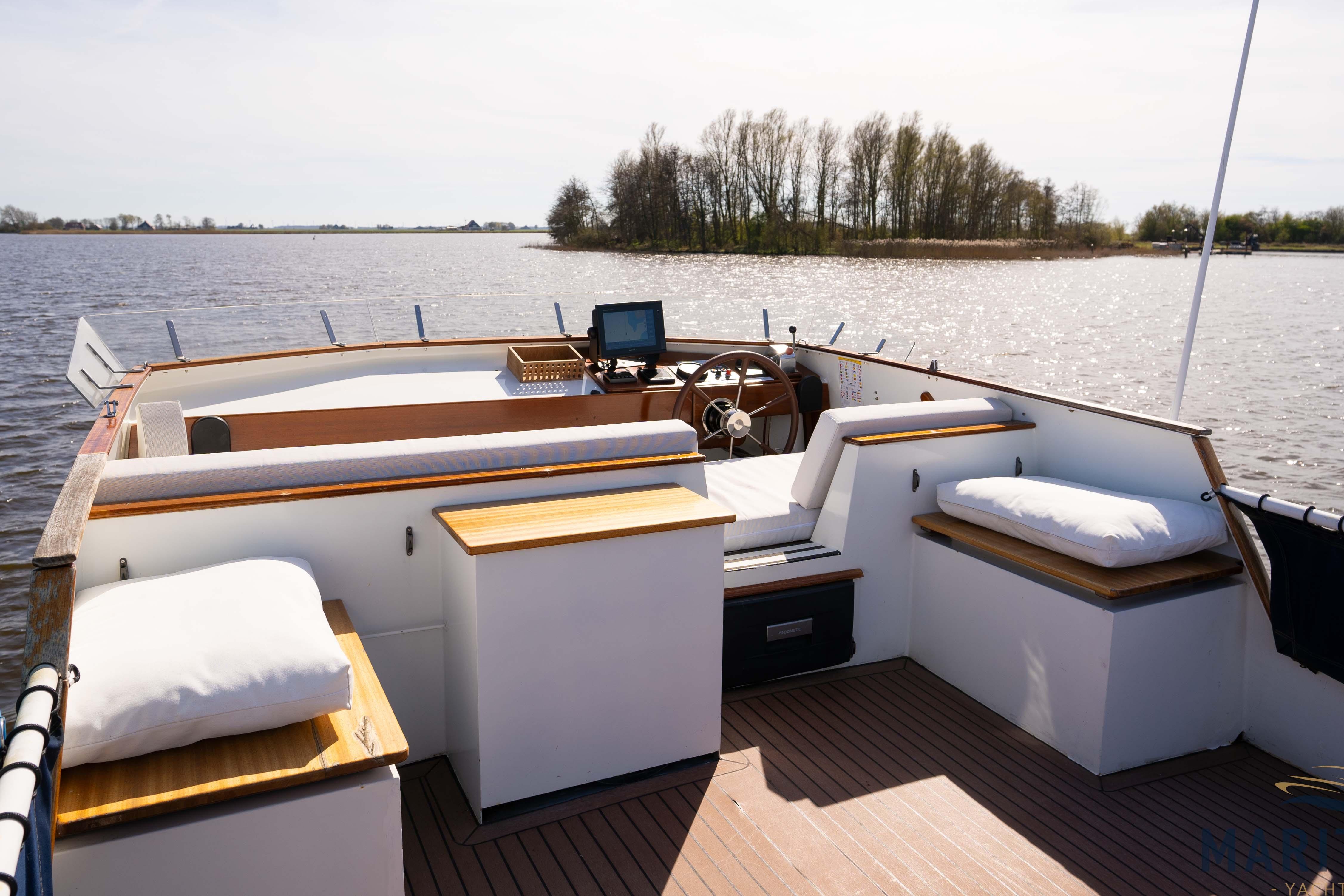 Elbtrawler 1095 boat interior, 1996 model, featuring spacious seating and steering area on a sunny day.