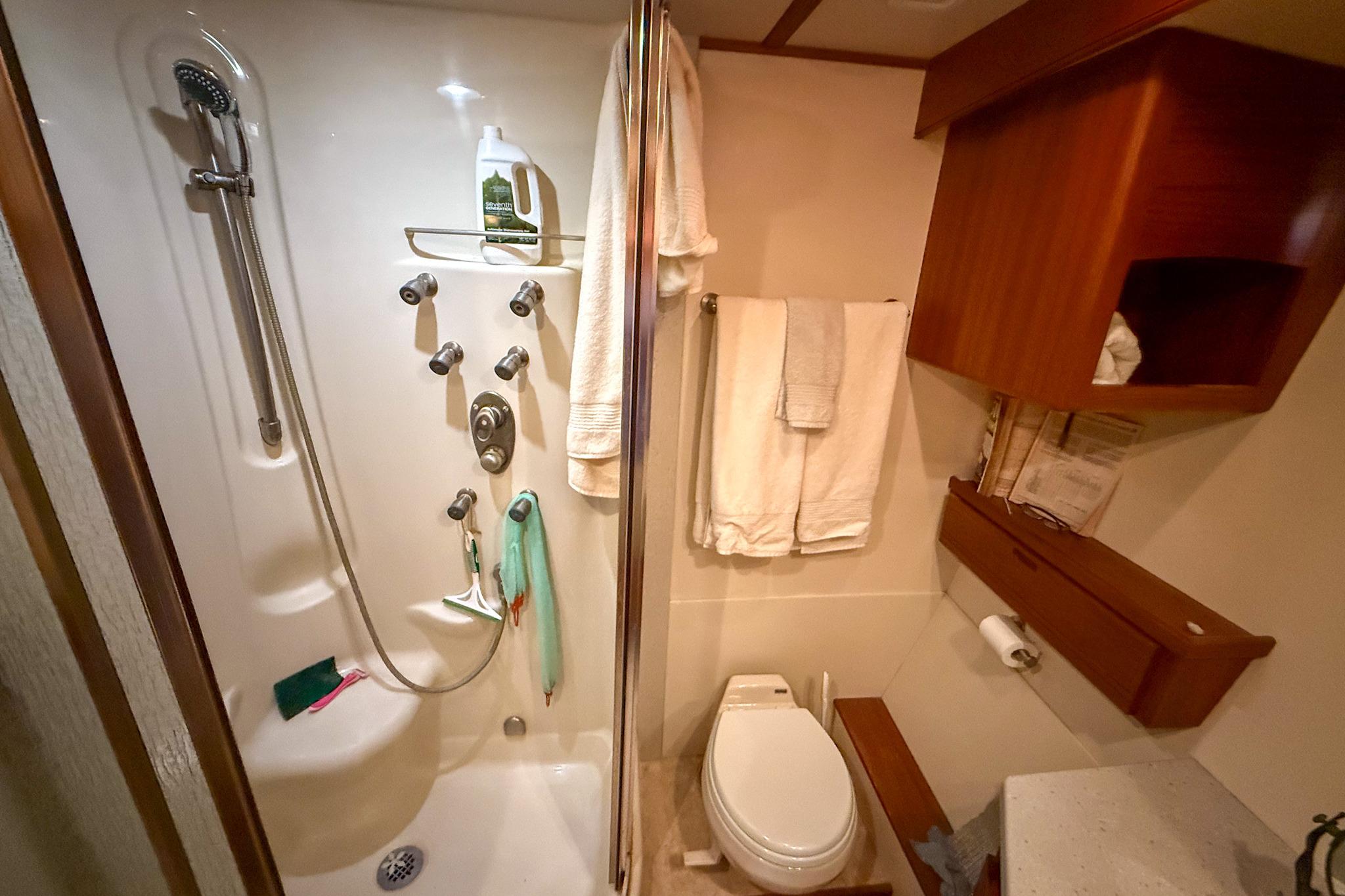 Compact bathroom in 2007 Nordic Tug 54 with shower, toilet, and wooden cabinetry.