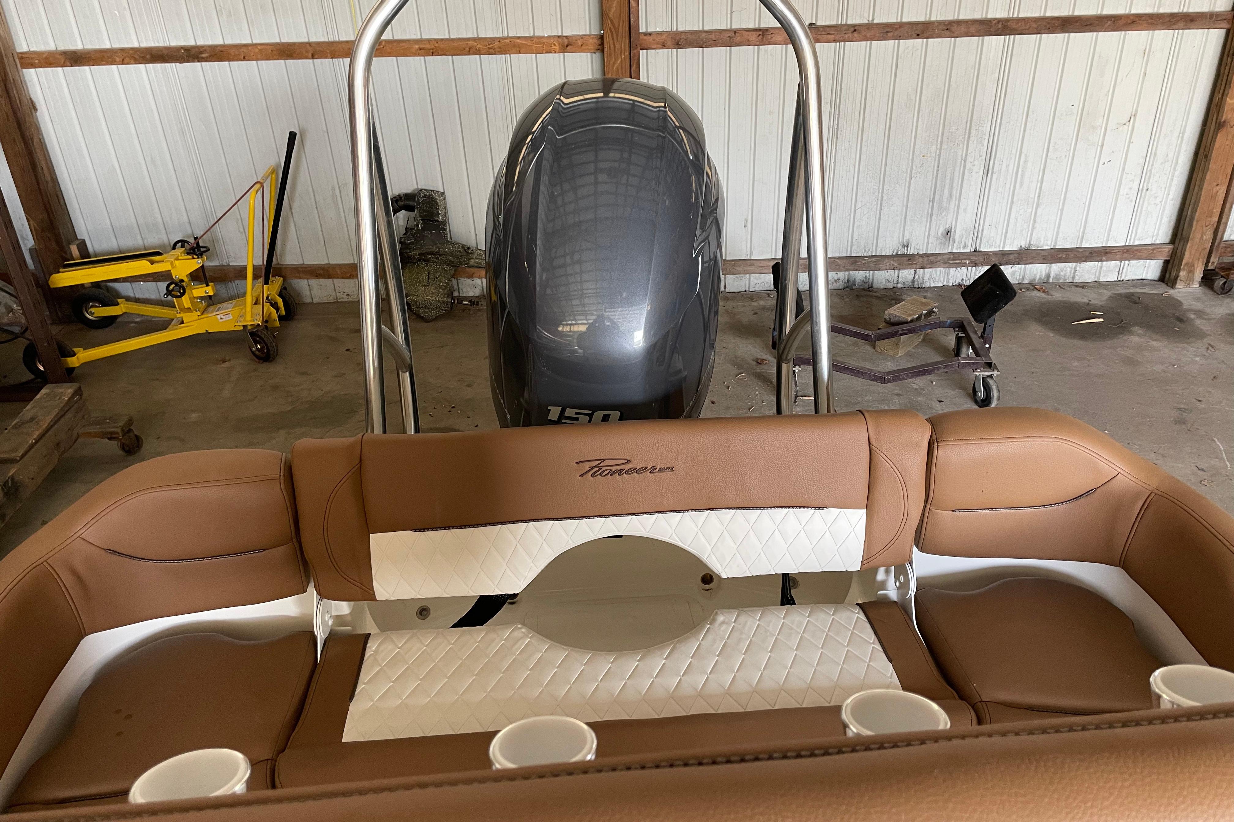 2026 Pioneer 202 Islander boat interior with brown seating and outboard motor in a garage.